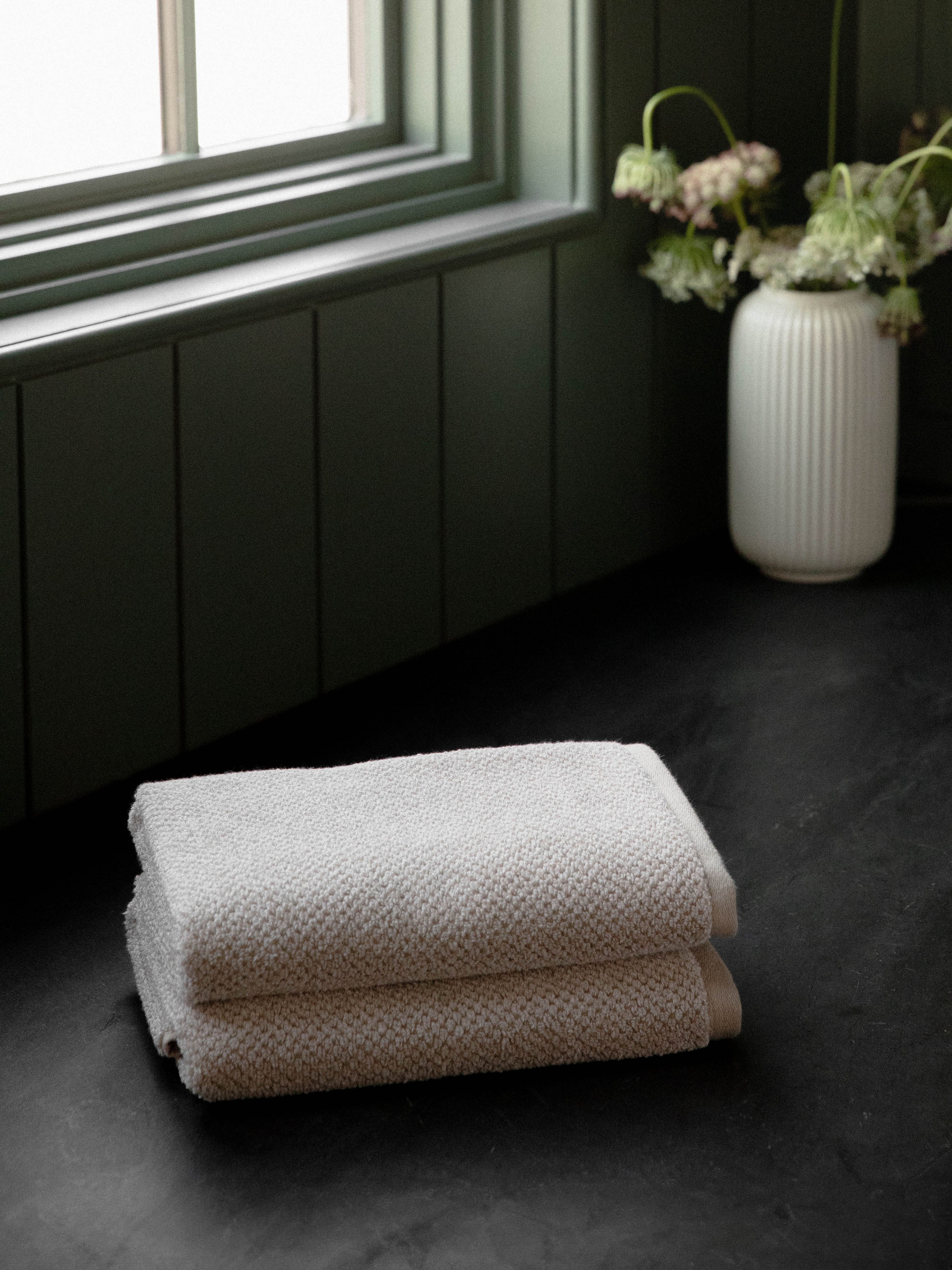 Nantucket Hand Towels in the color Heathered Sand. Photo of Nantucket Hand Towels taken with the Hand Towels resting on a countertop in a bathroom. |Color: Heathered Sand