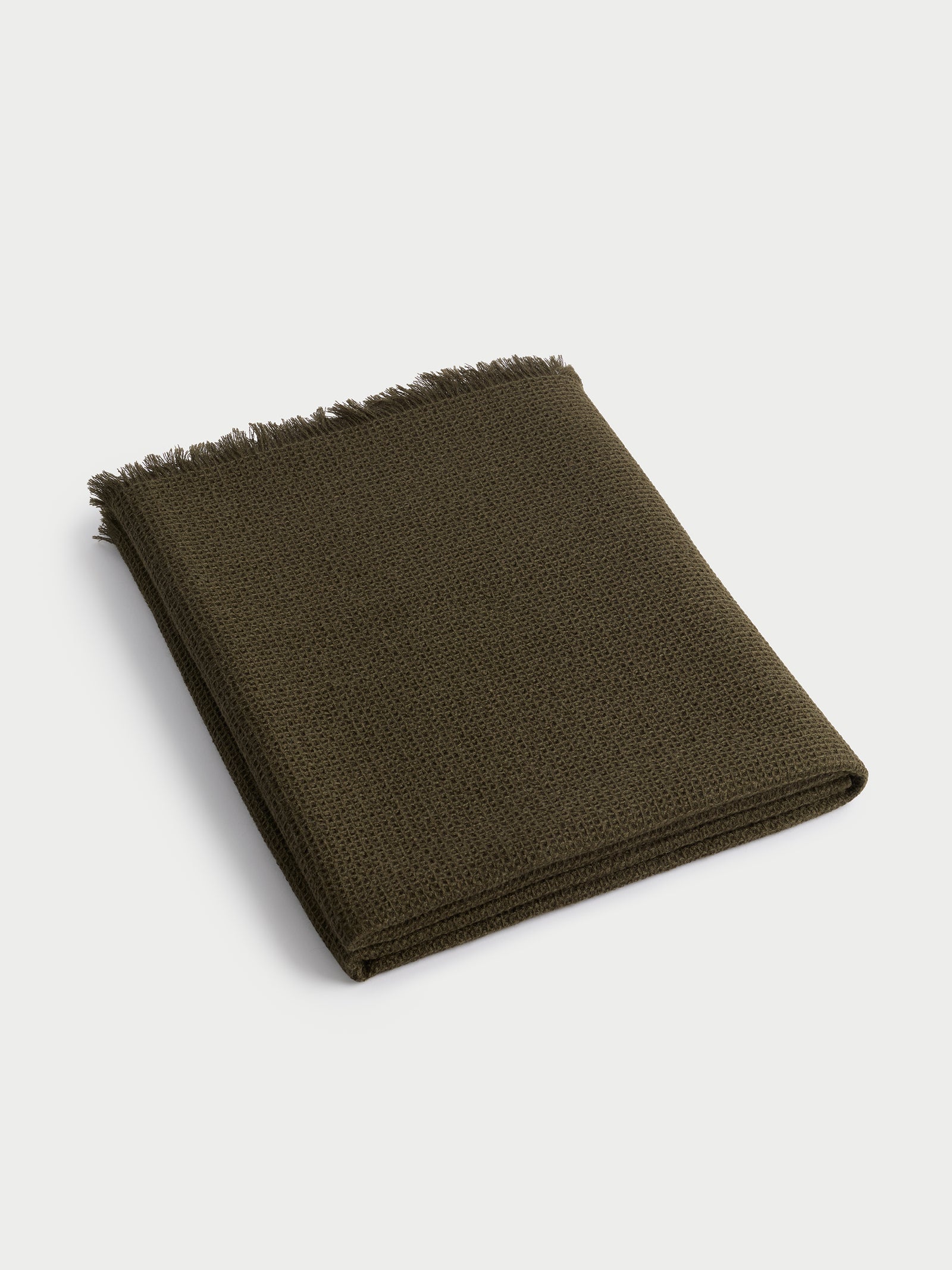 Folded utility green alpaca throw with white background 