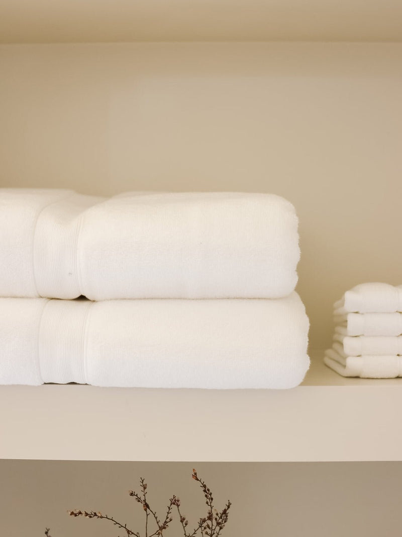 White luxe bath towels and washcloths folded on shelf