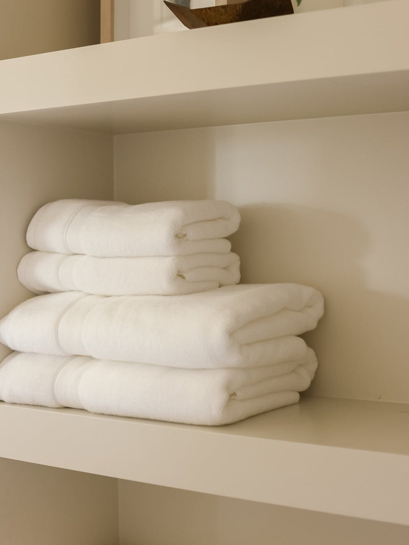 White luxe bath towels and hand towels folded on shelf