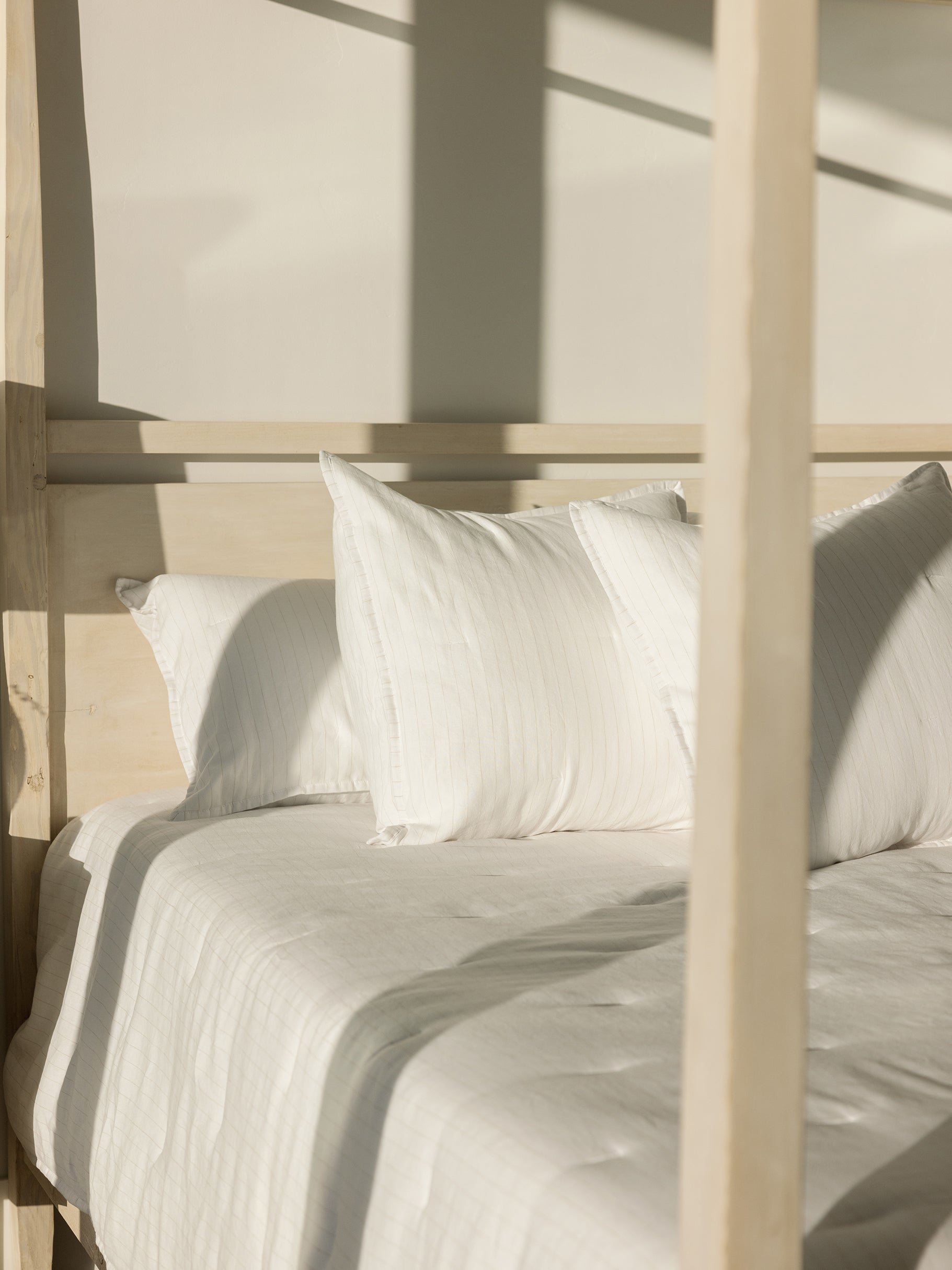 Bed made with flax pencil stripe shams and quilt 