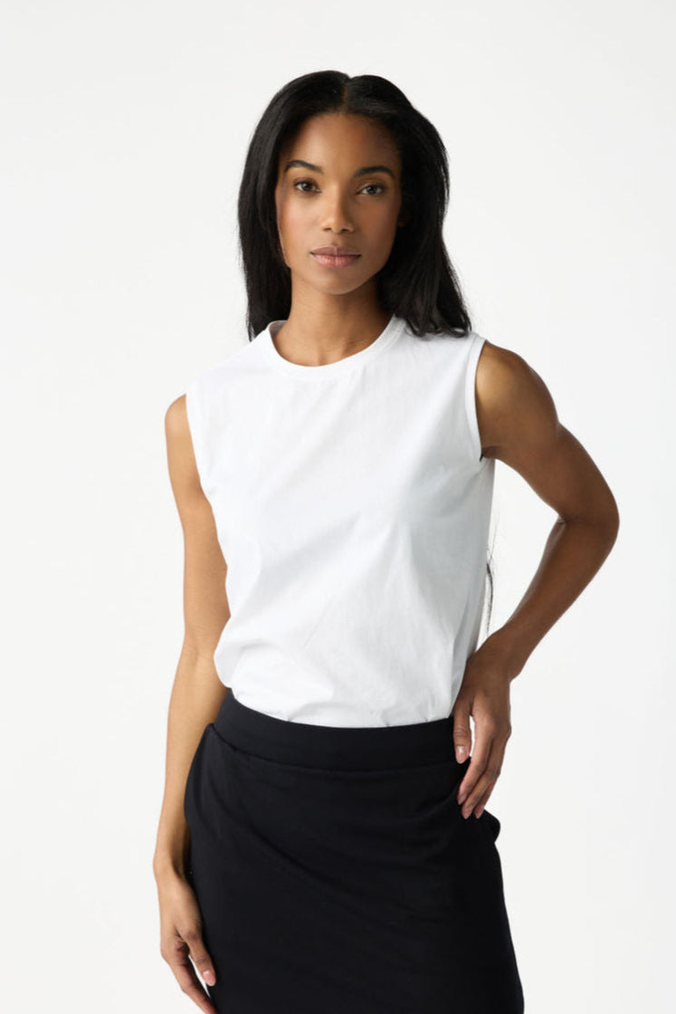 A woman with dark hair wears Cozy Earth Women's All Day Sleeveless Tee in White. She's shown from the hips up in front of a white background. 