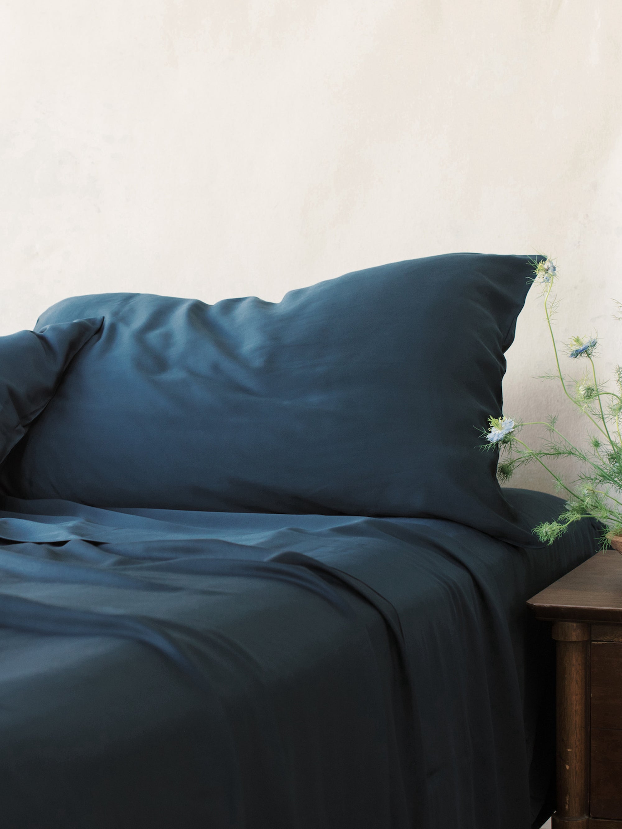 Unmade bed with navy bedding 