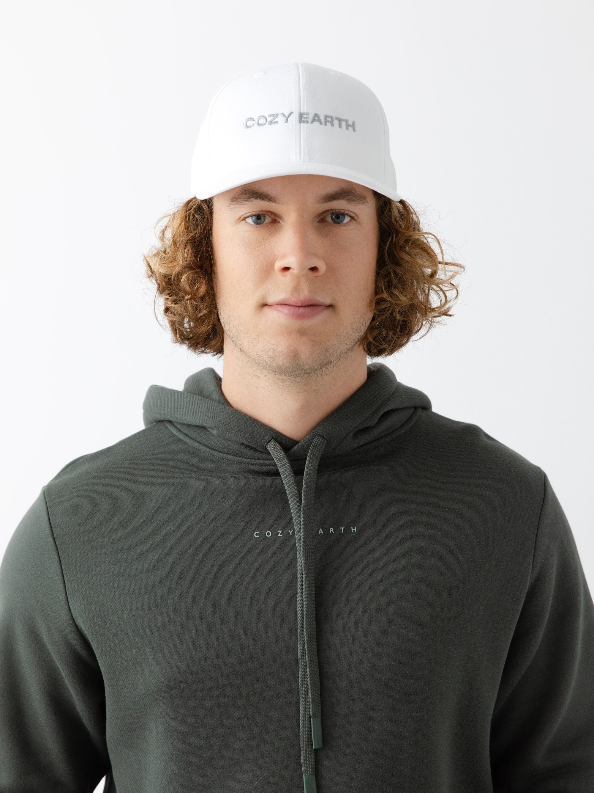 A man wearing a White cap with 'COZY EARTH' text on a white background 