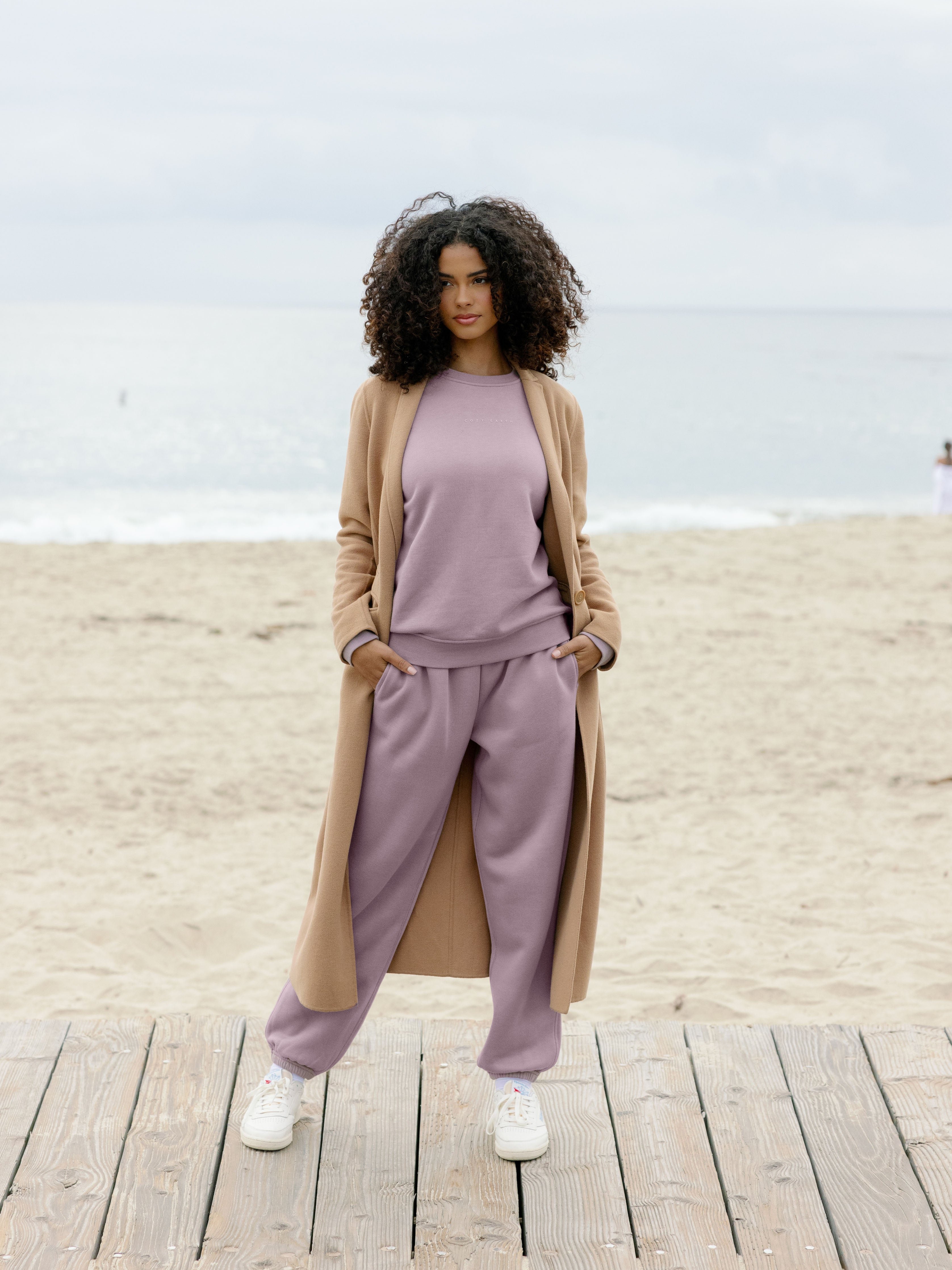 Woman wearing dusty orchid cityscape set on boardwalk with coat over it 