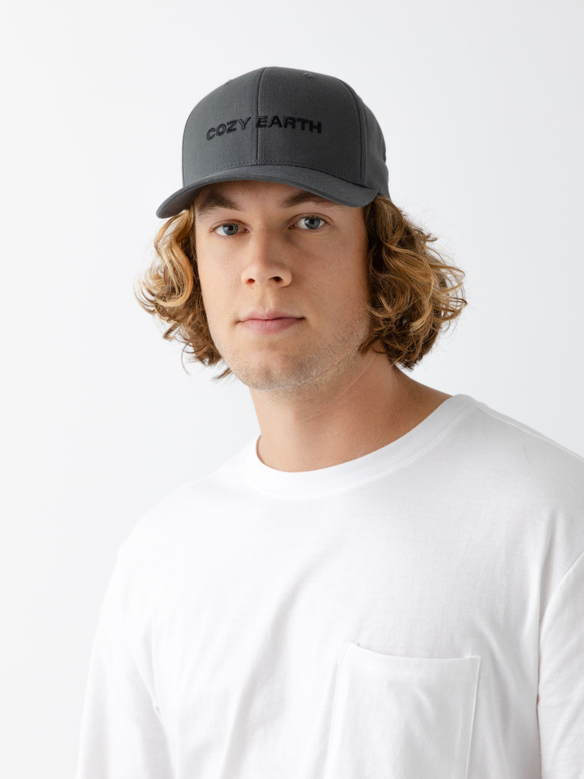 A man wearing a grey cap with 'COZY EARTH' text on a white background 