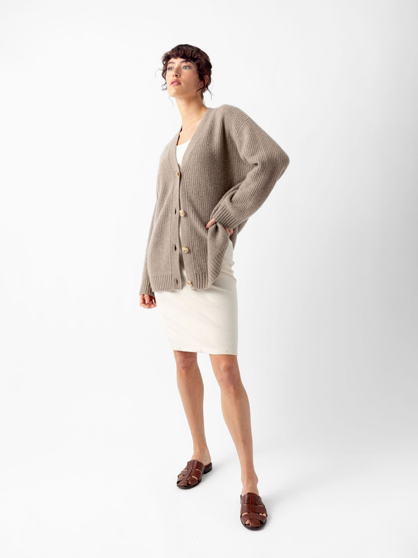 Woman in almond sunday cardigan over white dress with white background 
