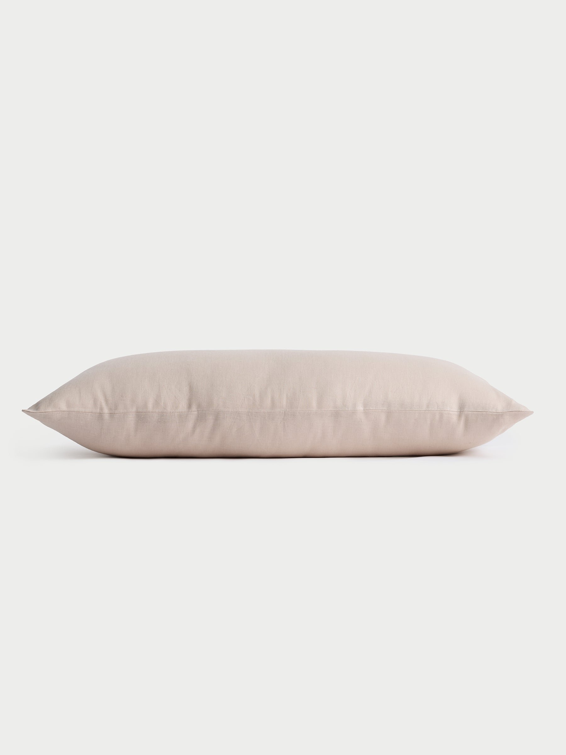 A side view of a rectangular Linen Throw Pillow in beige, set against a light background, by Cozy Earth. |Color:Birch|Size:14" x 30"