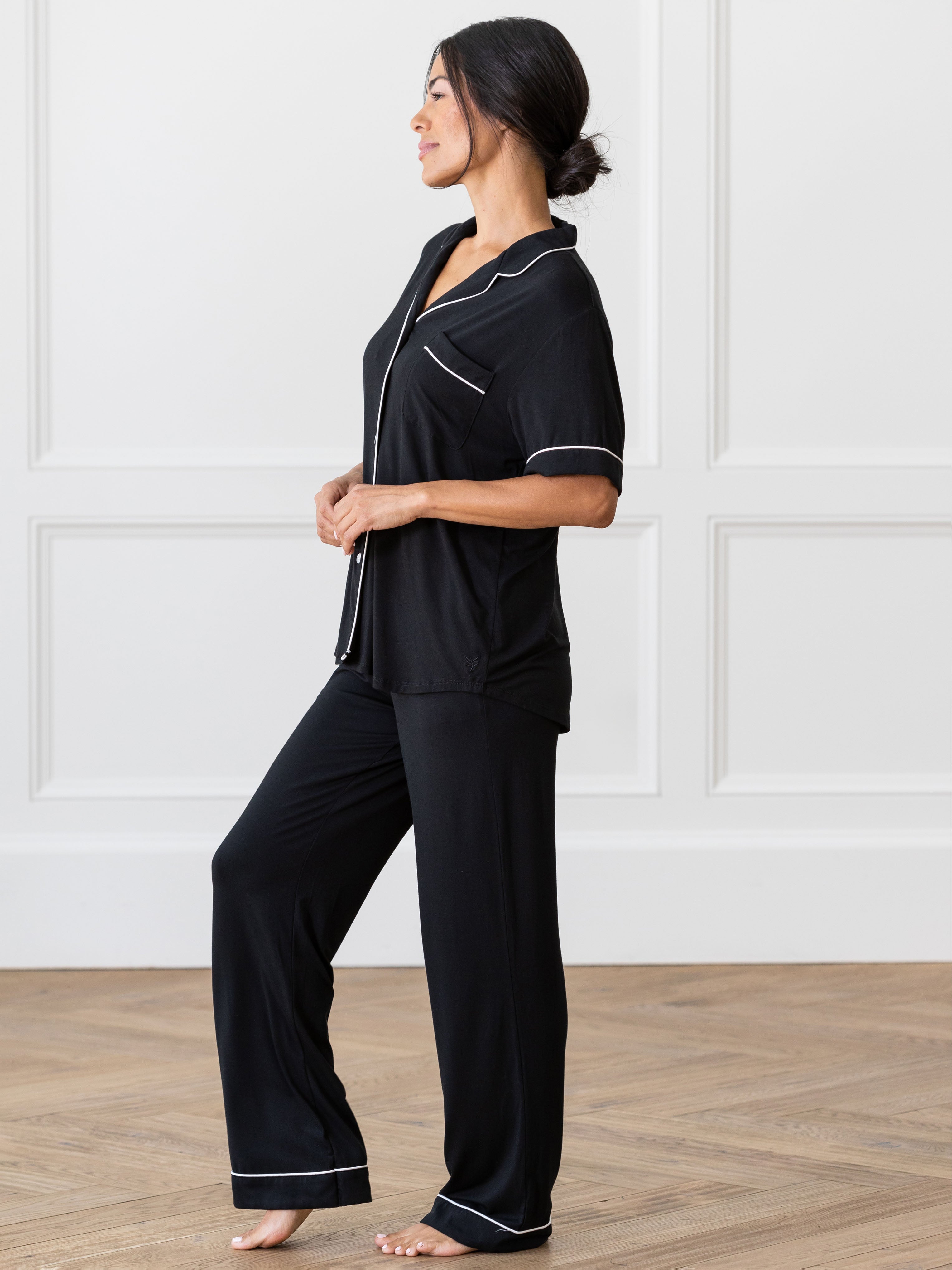 Black Short Sleeve & Pant Bamboo Pajama Set modeled by a woman. The photo was taken in a high contrast setting, showing off the colors and lines of the pajamas. |Color: Black