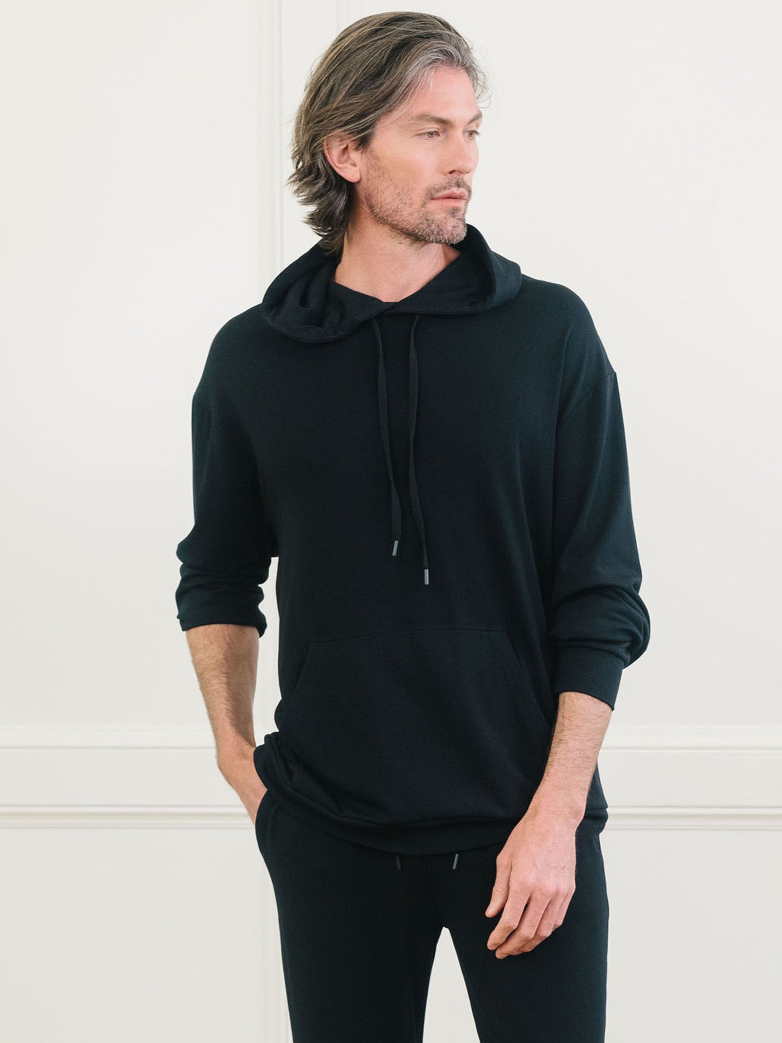 Black Bamboo Hoodie worn by man standing in front of white background.