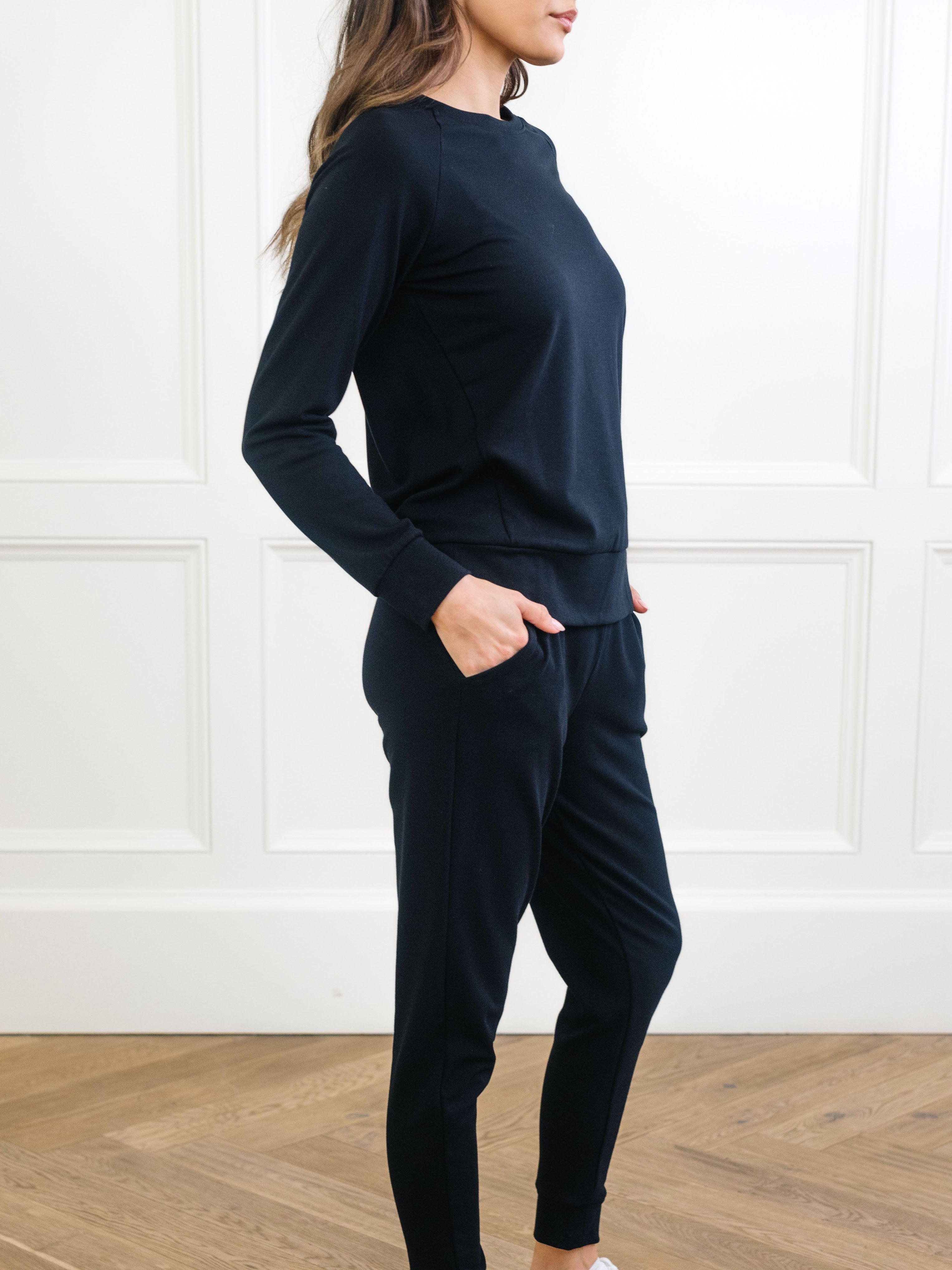 Black Bamboo Jogger Set modeled by a woman. The photo was taken in a high contrast setting, showing off the colors and lines of the pajamas. 