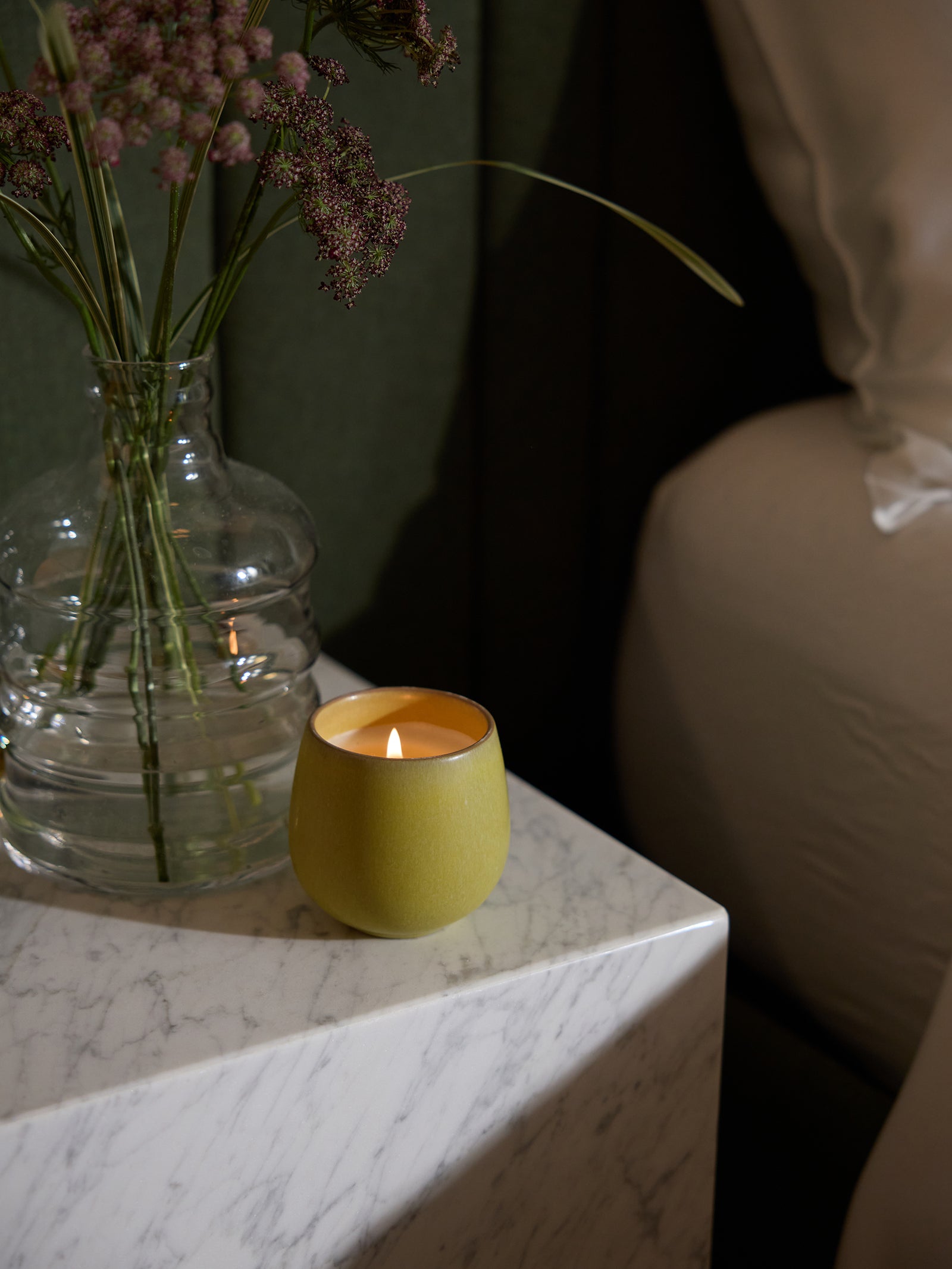 Cozy Earth Bloom Candle sits on a bedside table.