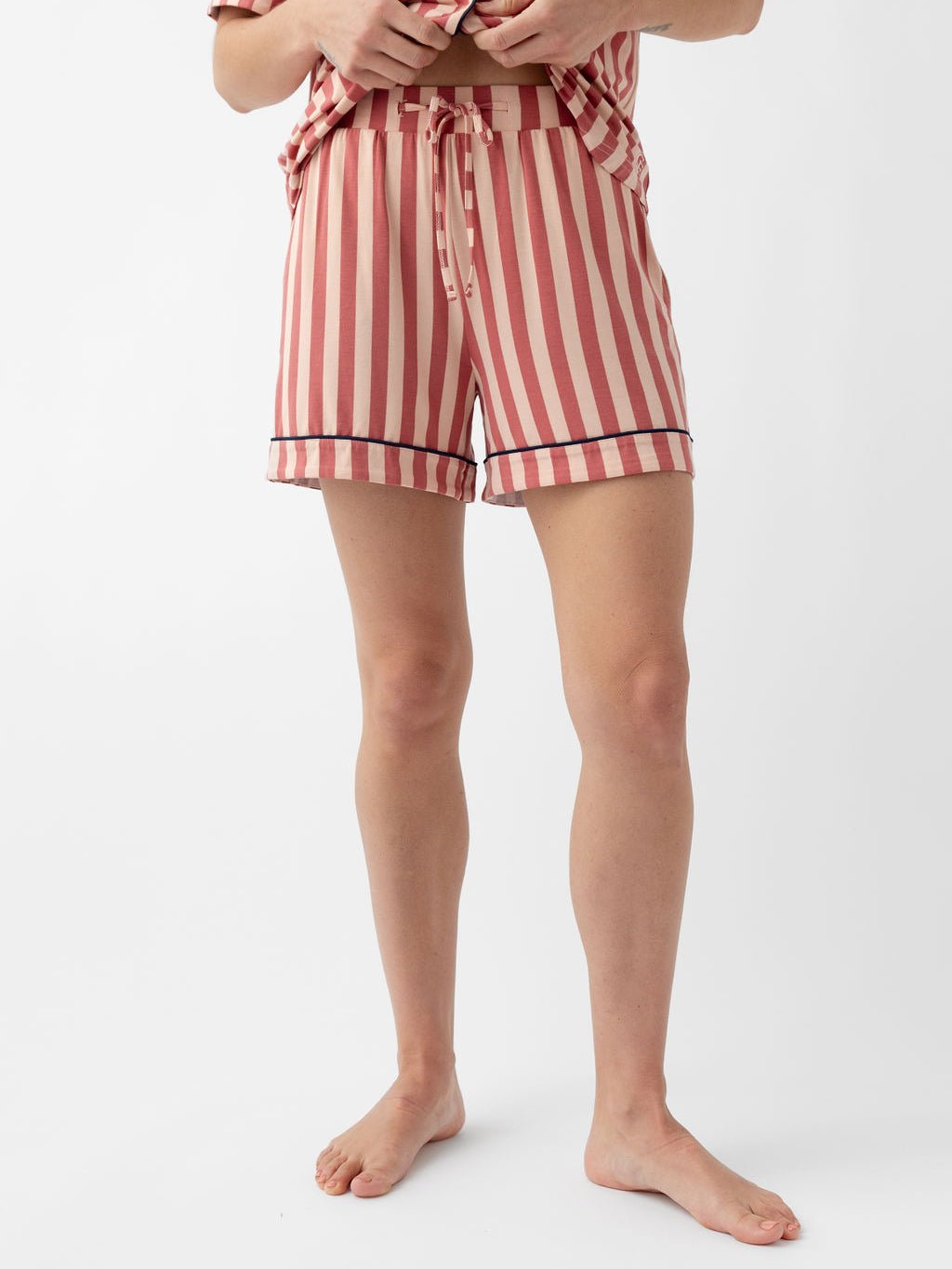 Woman wearing blush stripe pajama shorts with white background 