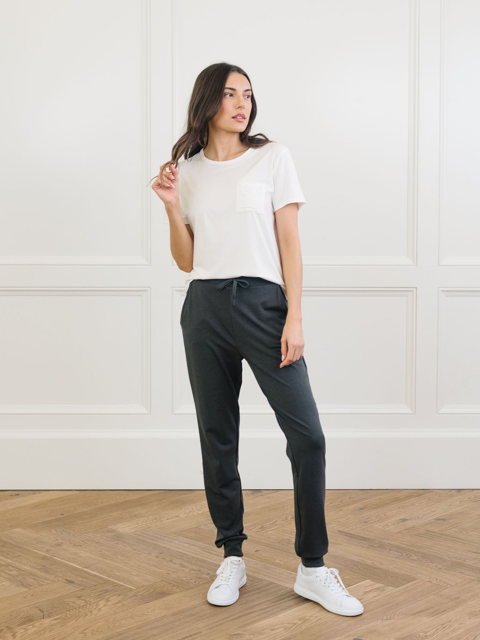 Charcoal Bamboo Jogger Set modeled by a woman. The photo was taken in a high contrast setting, showing off the colors and lines of the pajamas. 
