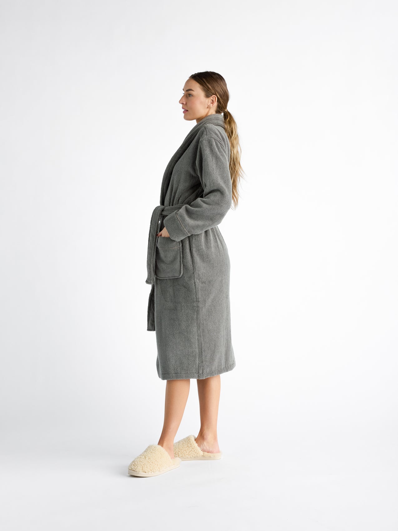 A profile view shows a woman in a Cozy Earth's Luxe Bath Robe, grey with shawl collar, pockets, and a belt. 