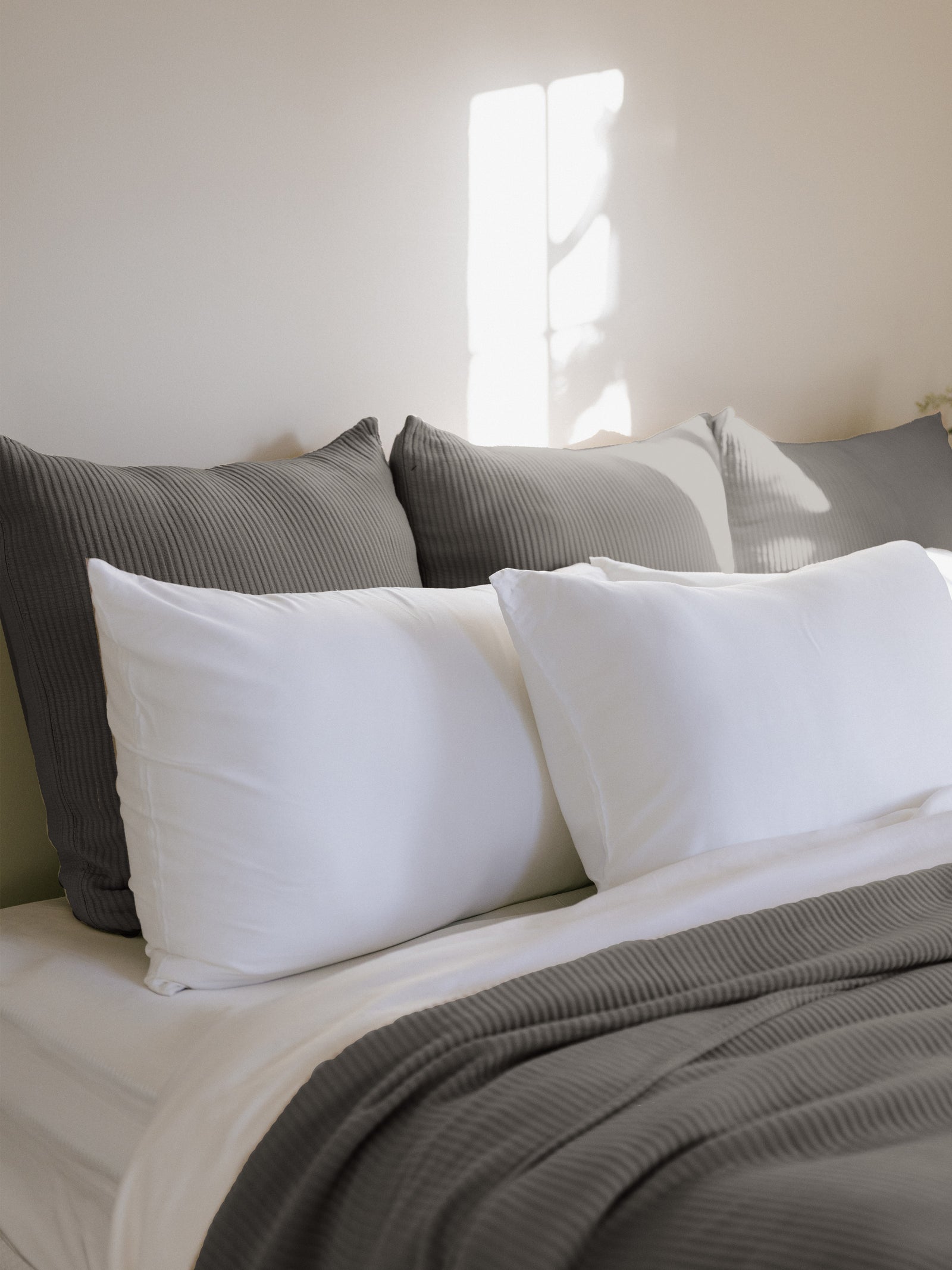 Charcoal euro coverlet shams behind white pillows on a bed 