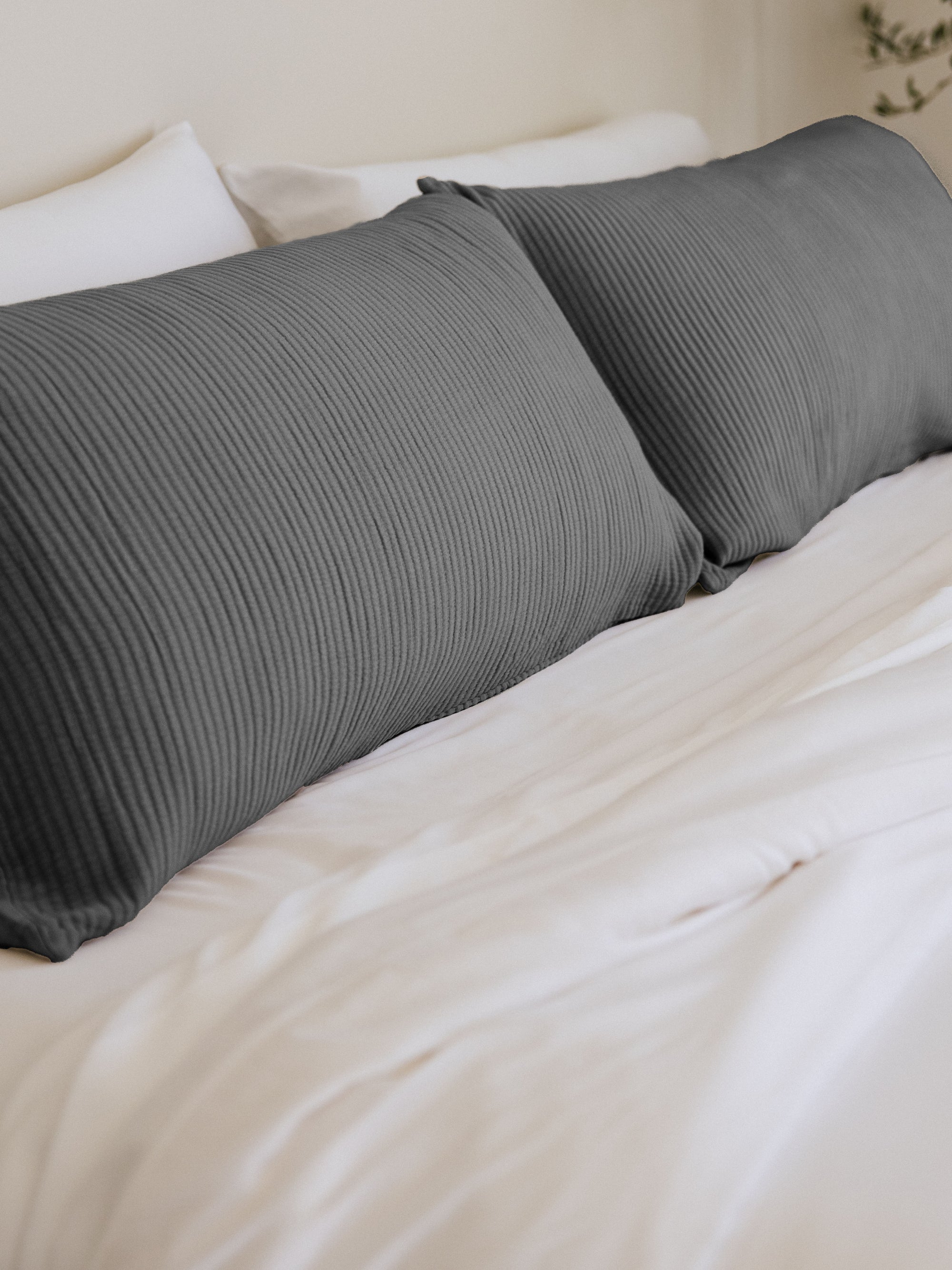 Charcoal coverlet shams on white bed 