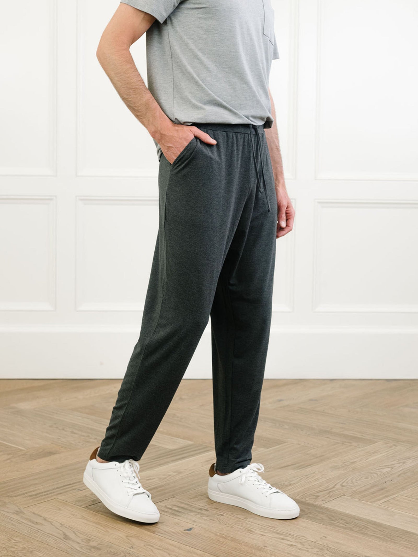 Man in charcoal pajama pants in room with wooden floor 