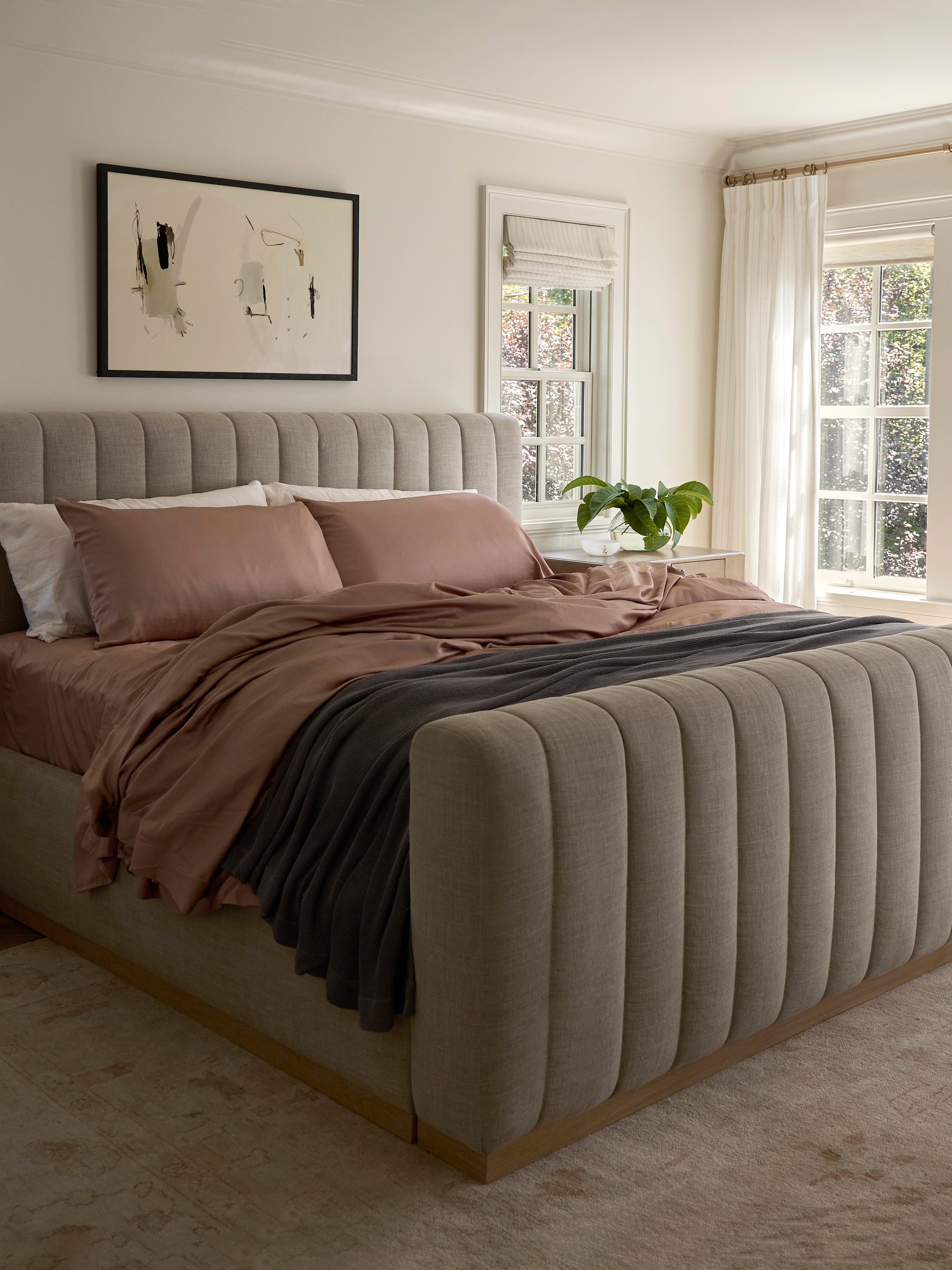 Bed with clay bedding and a charcoal blanket draped across 