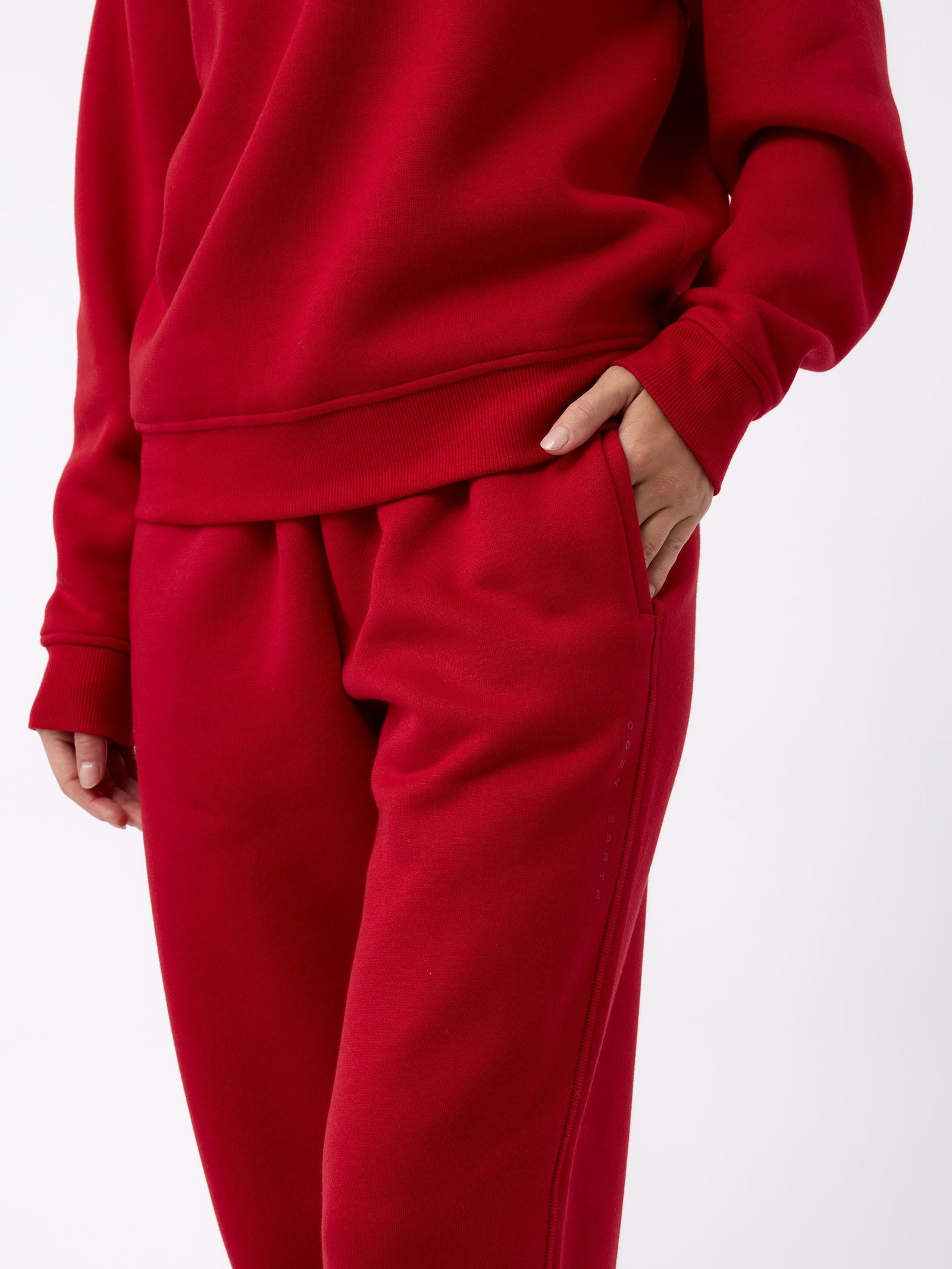 A person is wearing the Women's CityScape Wide Leg Pant by Cozy Earth in a striking red color, with one hand tucked into the pocket. The fabric looks incredibly soft and comfortable, and the outfit is showcased against a simple white background. 