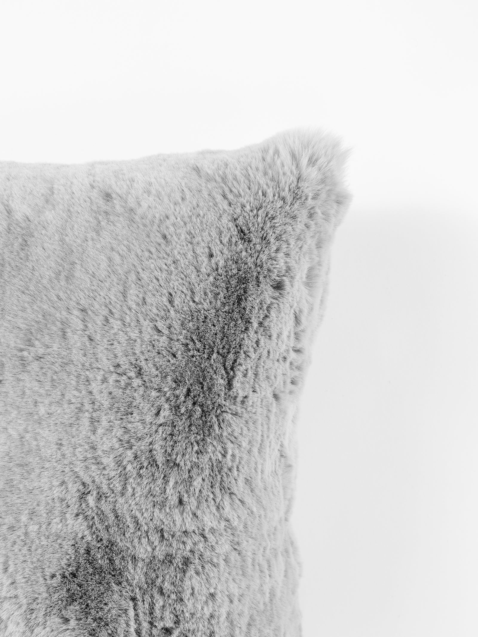 Close-up of the Cuddle Pillow from Cozy Earth, featuring its soft, fluffy gray surface against a white background. The texture appears plush and cozy, showcasing a visibly dense pile. 