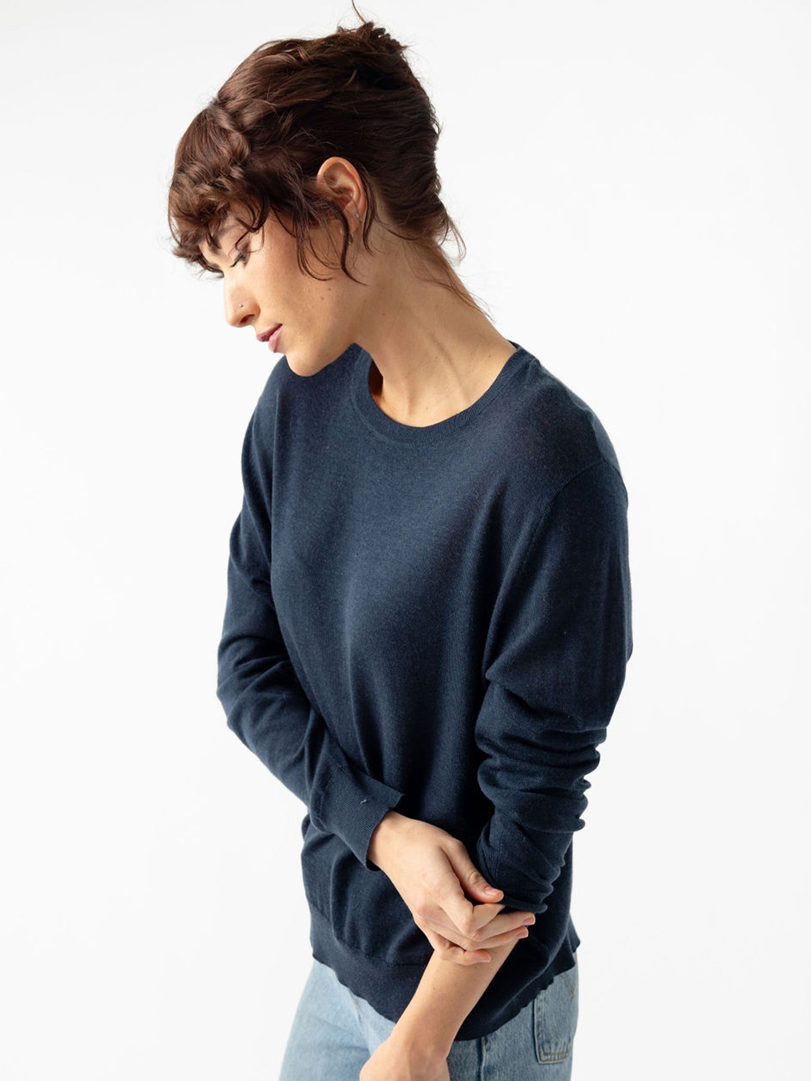 Side view of woman wearing jeans and an eclipse airknit sweater with white background 