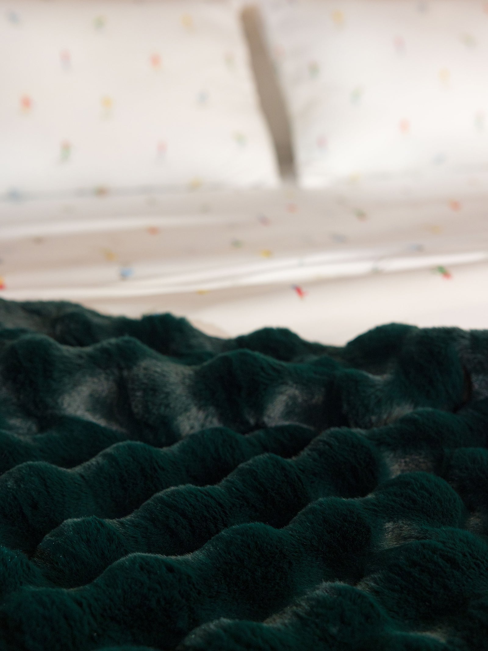 Close up of emerald bubble cuddle blanket on bed 