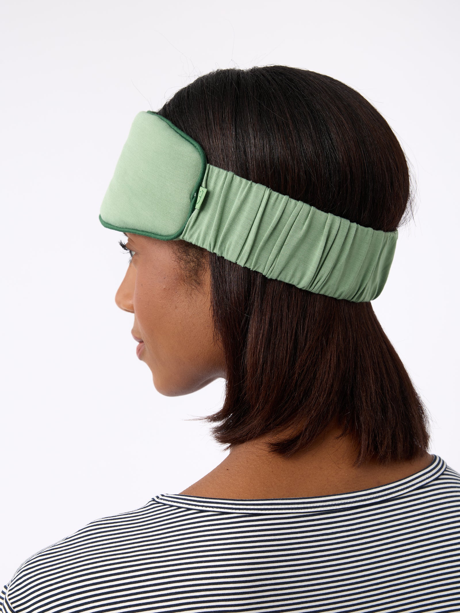 Back of woman's head with fern sleep mask on 