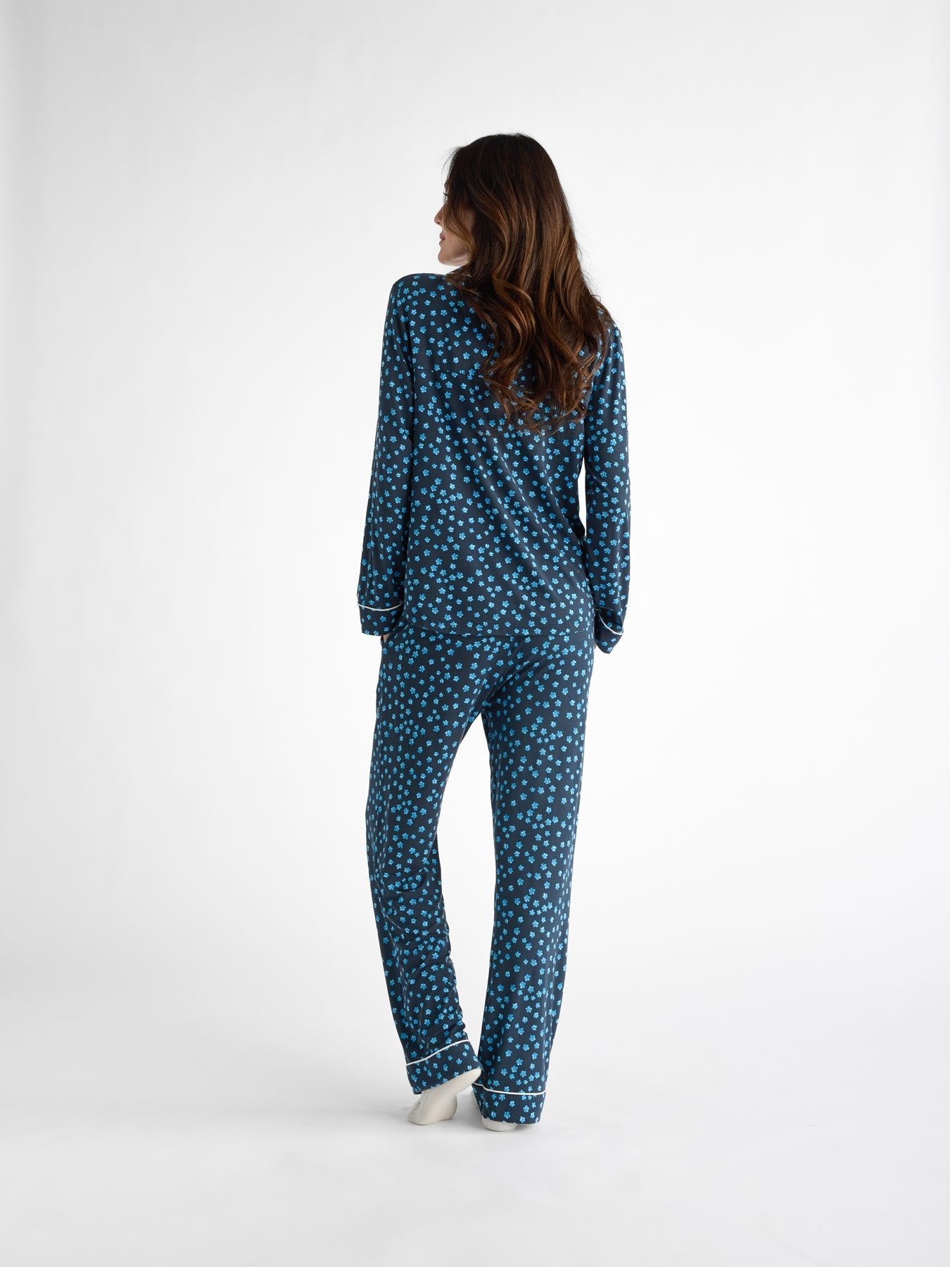 A person with long brown hair is shown from behind on a plain white background, wearing the Cozy Earth Women's Bamboo Stretch-Knit Pajama Pant in blue with white polka dots. 