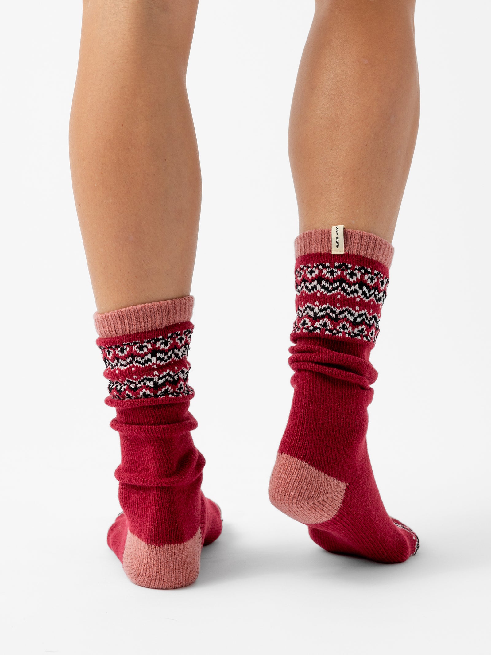 A person stands facing backwards in front of a white background wearing Fair Isle Plush Lounge Socks in Garnet. 