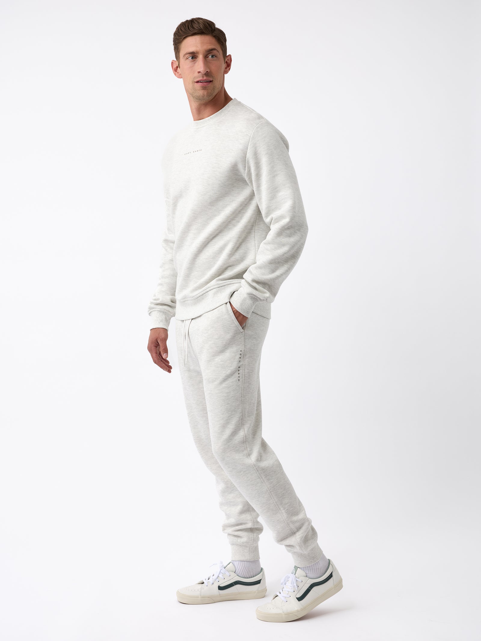 A person stands against a white background, dressed in the Men's CityScape Jogger by Cozy Earth, paired with white sneakers. The outfit exudes a casual and comfortable vibe. 