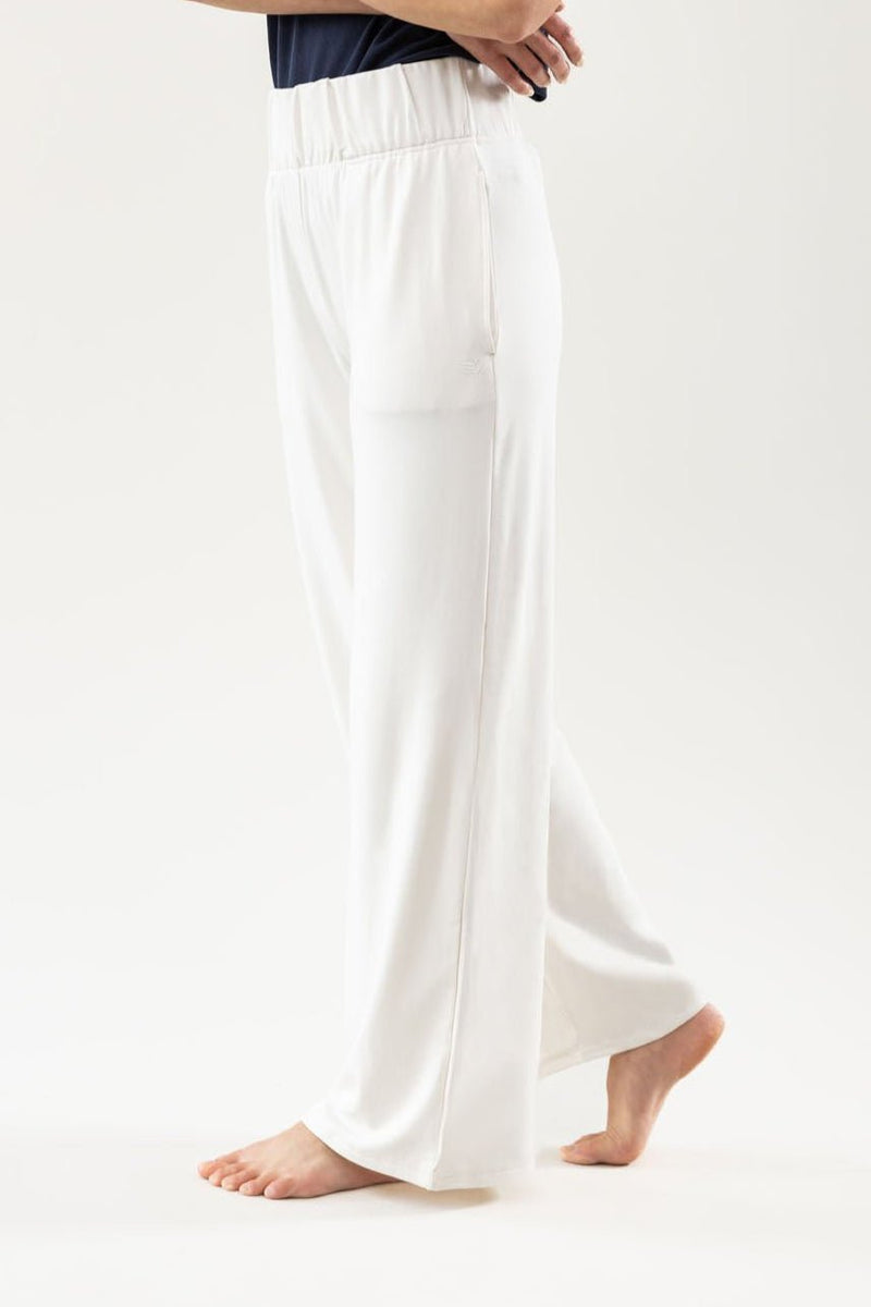 A person wearing the Cozy Earth Women's Ultra-Soft Bamboo Wide Leg Pull On Pant & Pullover Set stands barefoot with arms crossed against a plain light background.