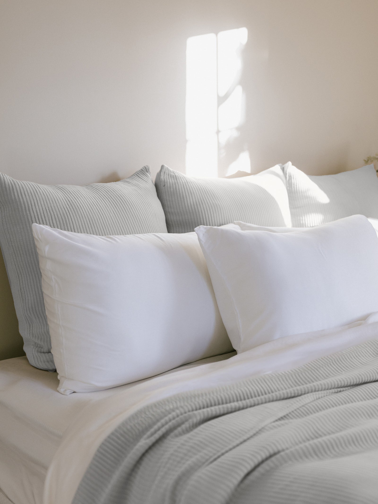 Light Grey euro coverlet shams behind white pillows on bed 