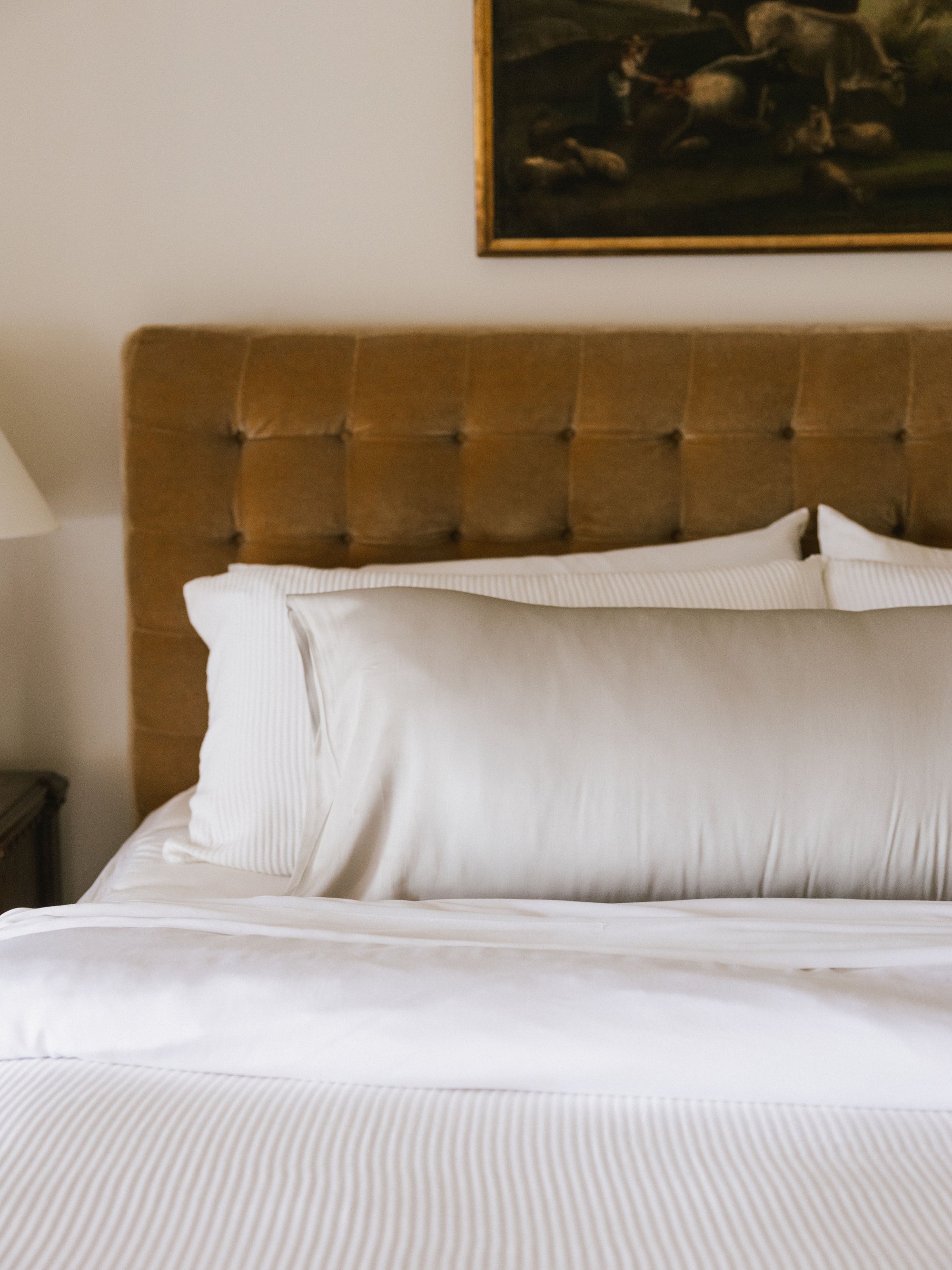 Partial view of light grey body pillow on bed 