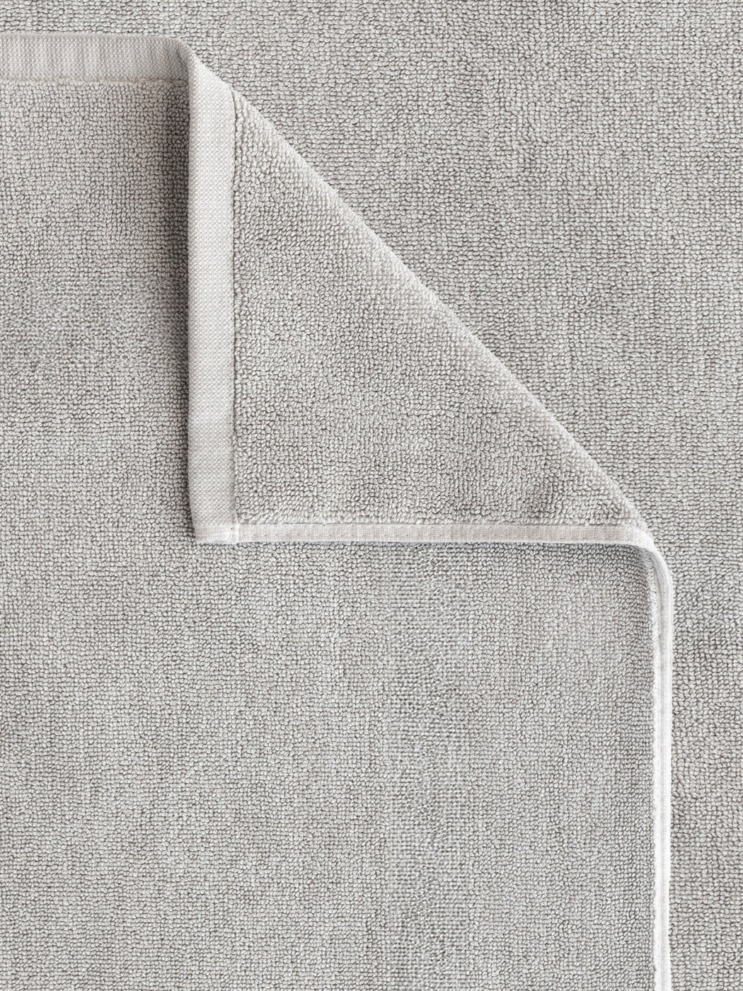 The Cozy Earth Loop Terry Bath Mat, shown in light grey, is neatly folded at one corner to display both sides and its detailed edge stitching. The soft, absorbent texture enhances comfort and style in any bathroom setting.|Color:Light Grey