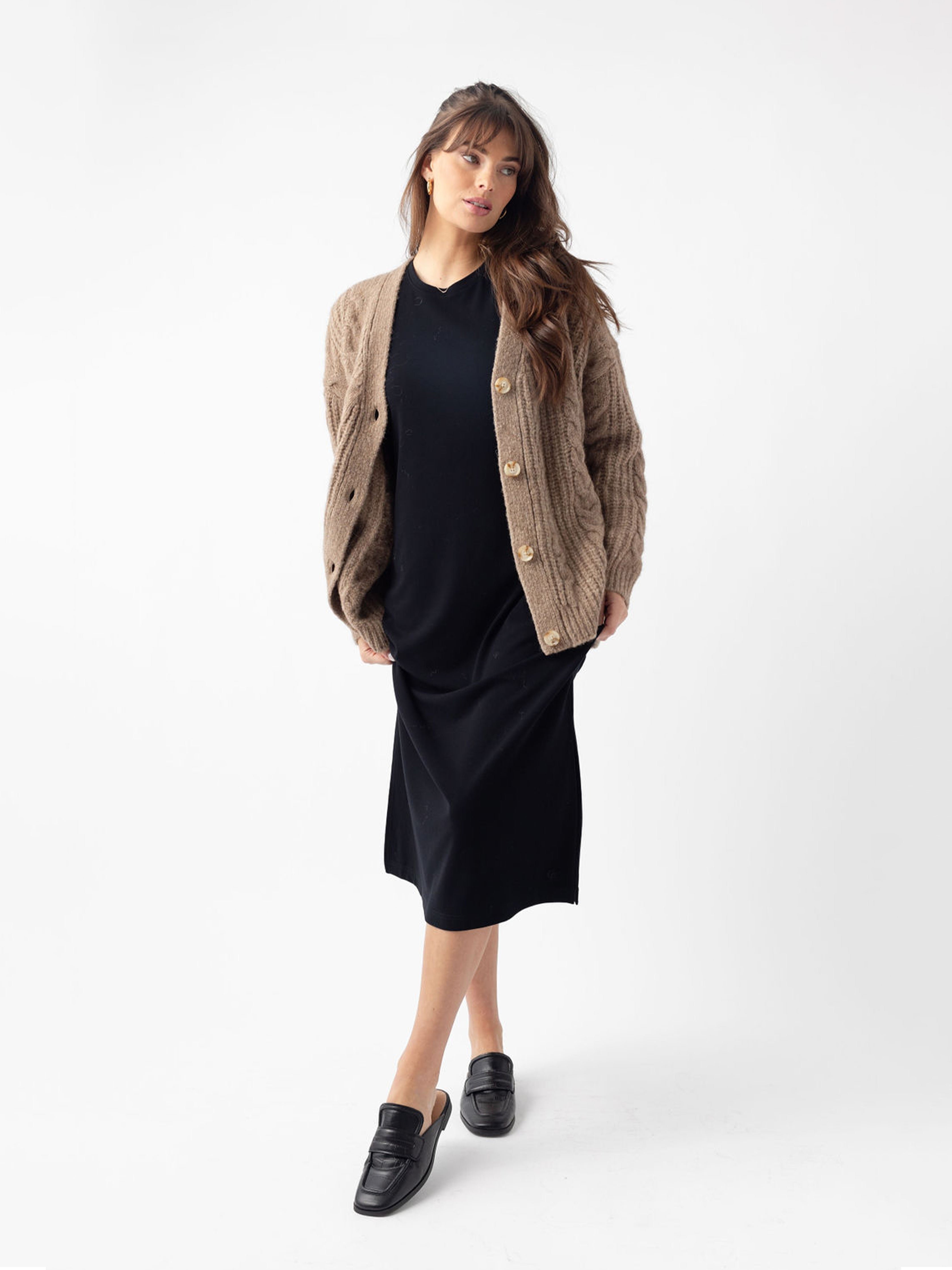 Woman in black dress and mushroom cardigan with white background 