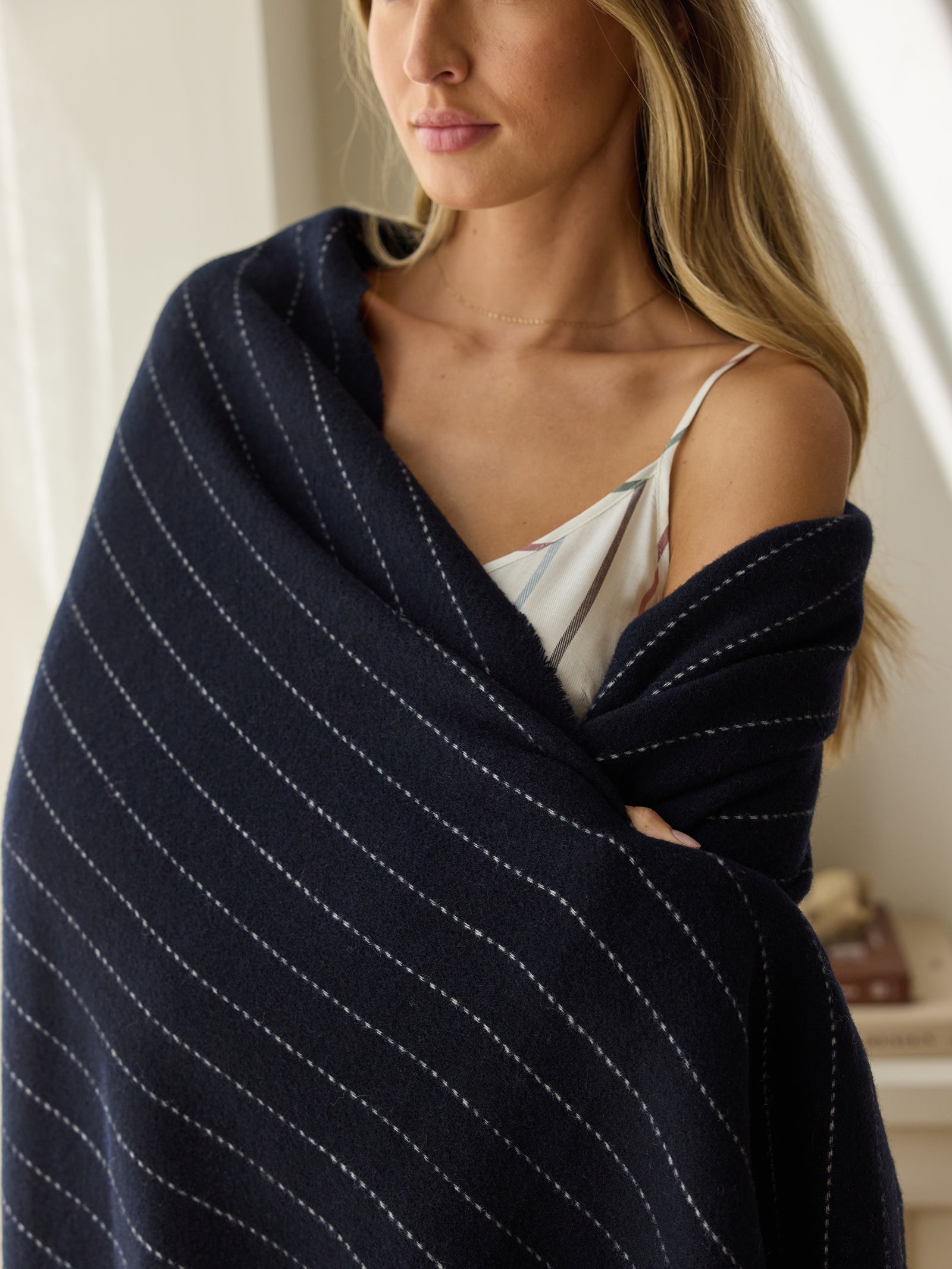 Woman standing with navy florence throw wrapped around her 