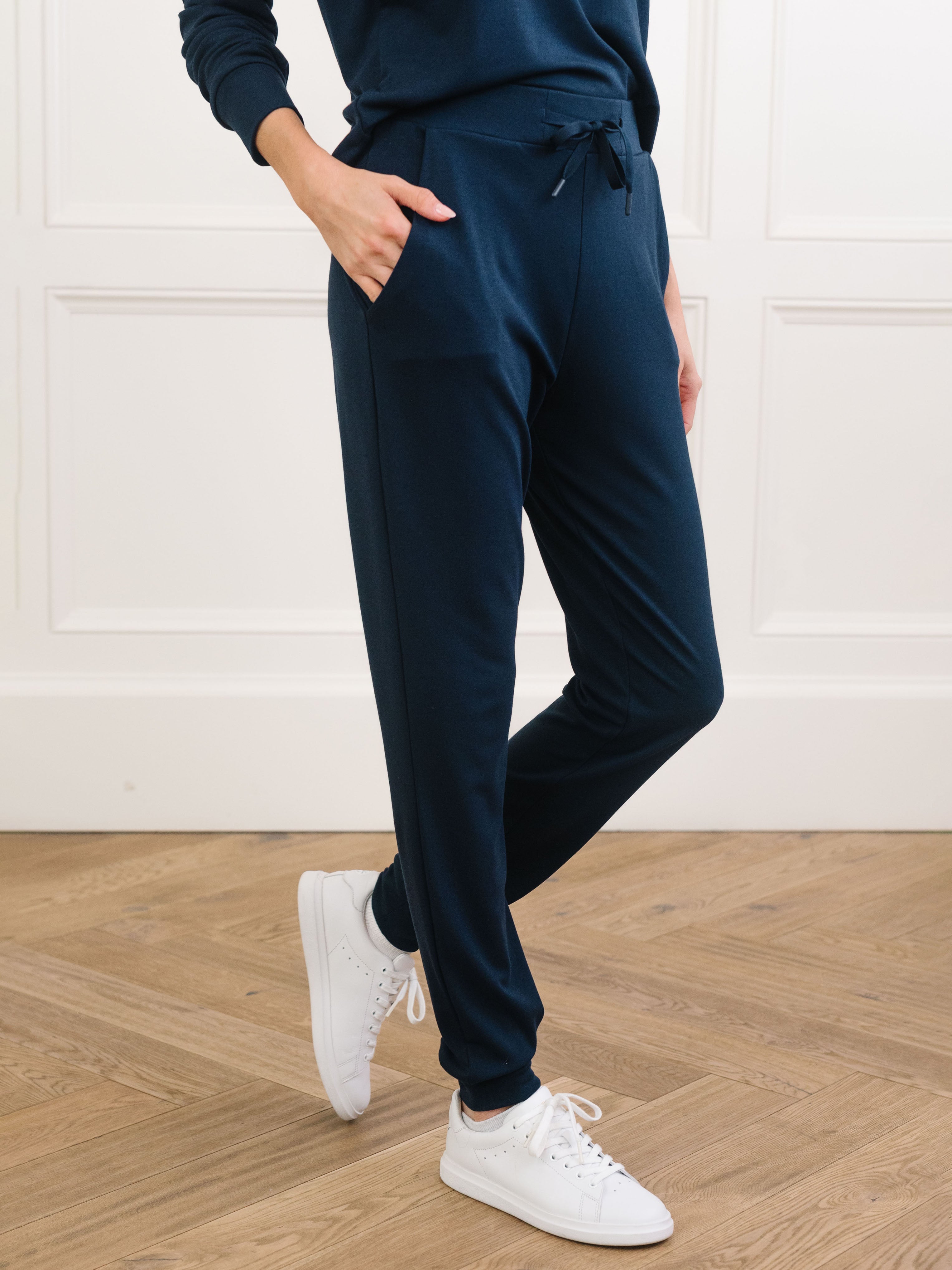 Navy Bamboo Jogger Set modeled by a woman. The photo was taken in a high contrast setting, showing off the colors and lines of the pajamas. |Color: Navy
