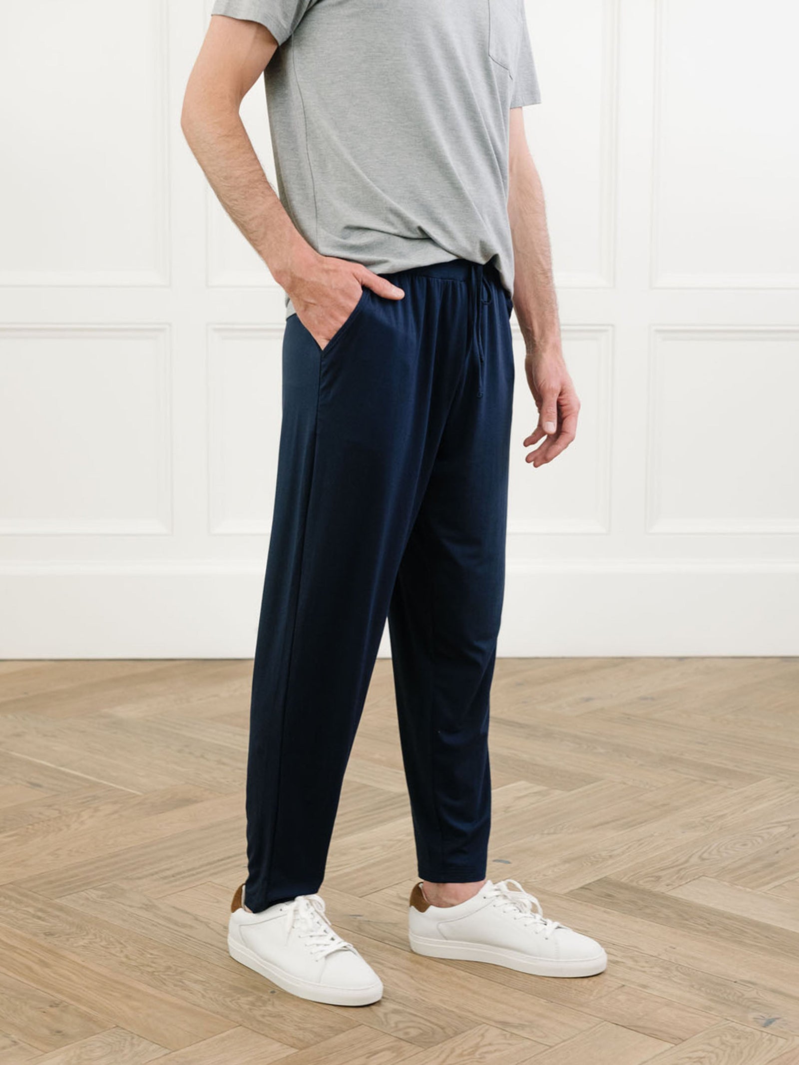 Man in navy pajama pants in room with wooden floor 