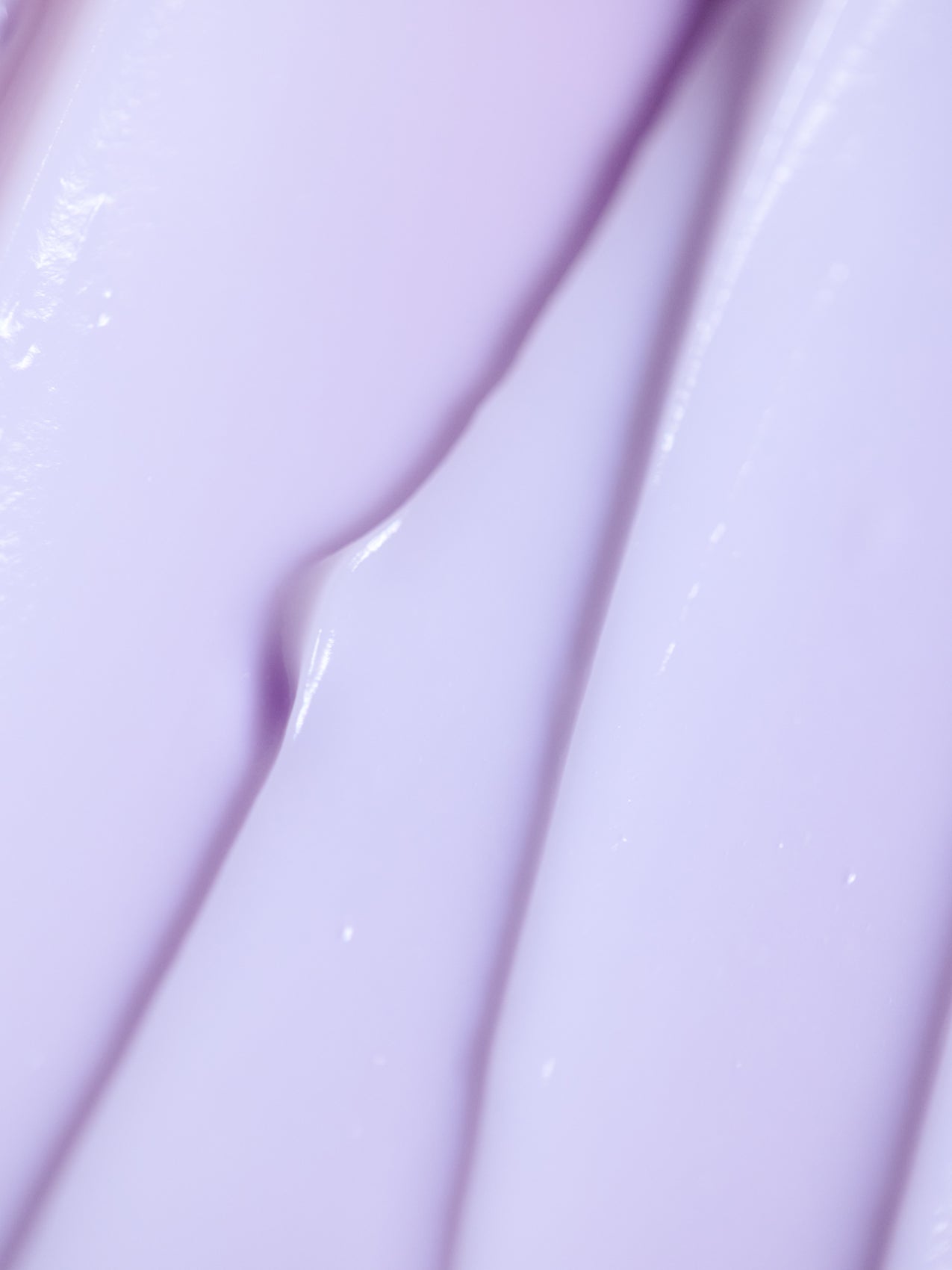 Close-up of Cozy Earth's Night Cream, showcasing its smooth purple texture with light reflections forming an abstract pattern of creamy ridges and folds. |Size:2 OZ