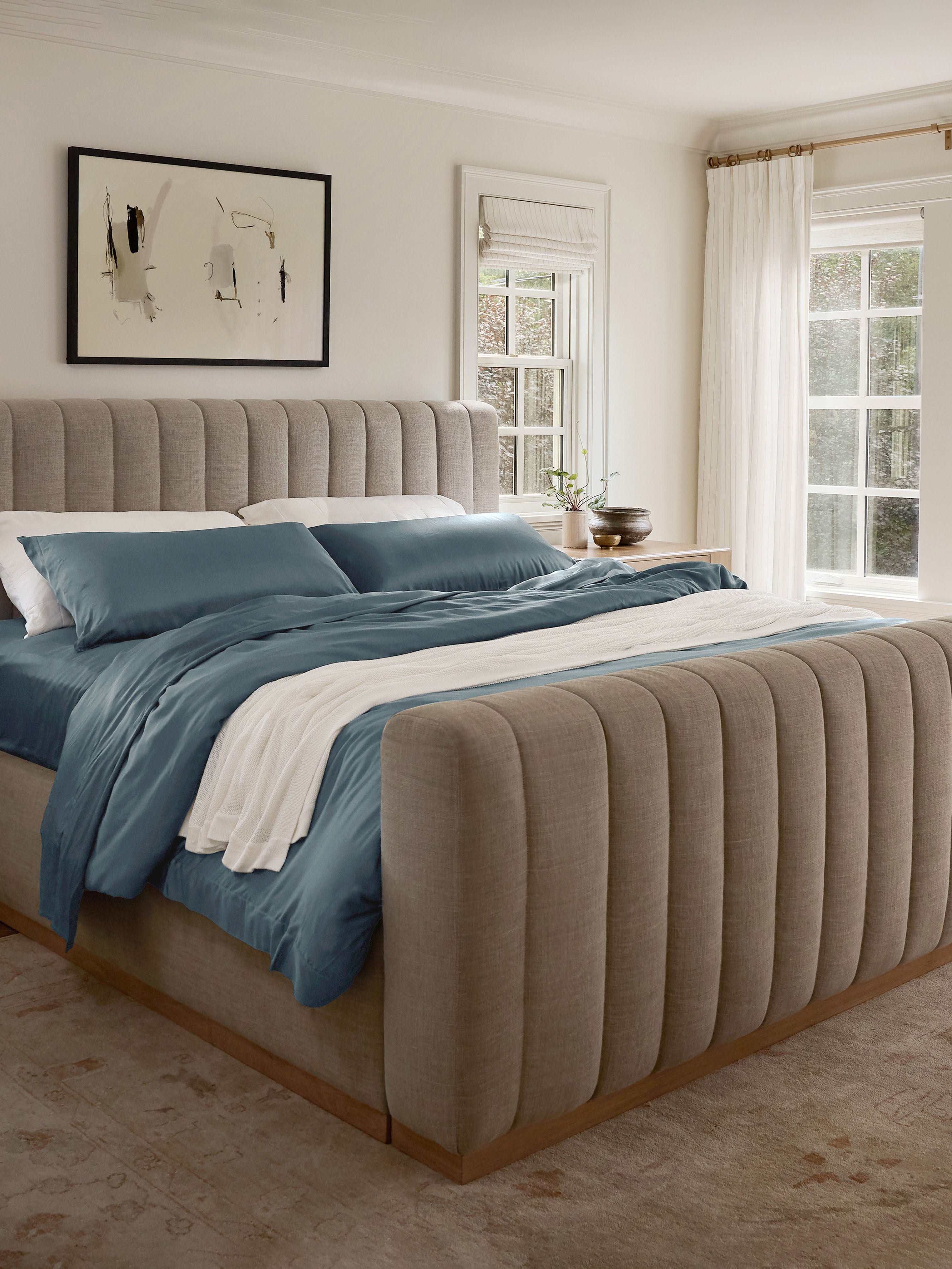 Bed with pacific blue bedding and a blanket draped across 