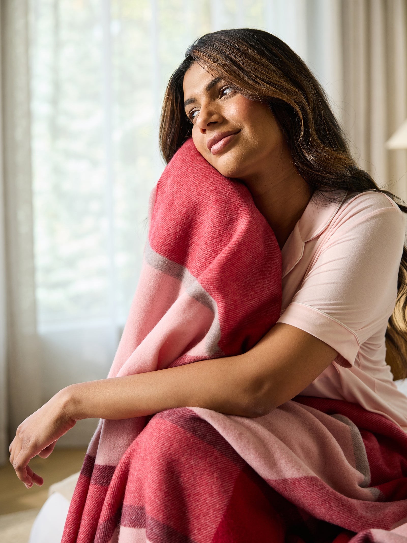 Woman sitting with pink lucca throw 