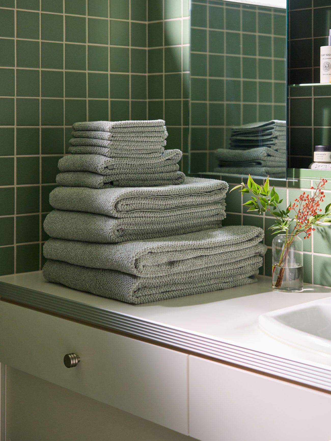 The Complete Nantucket Bath Bundle is shown sitting on a bathroom vanity countertop with a green tiled wall in the background. |Color:Heathered Sage