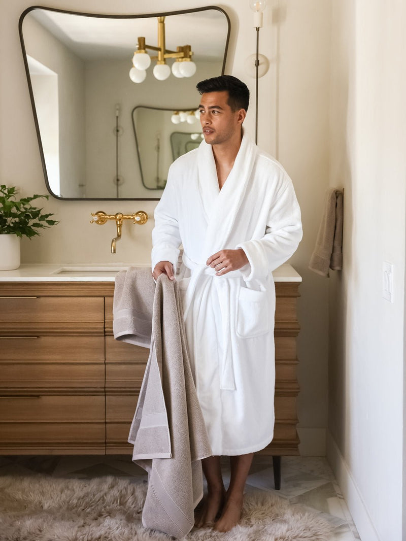 Man in white robe holding sand luxe bath towel