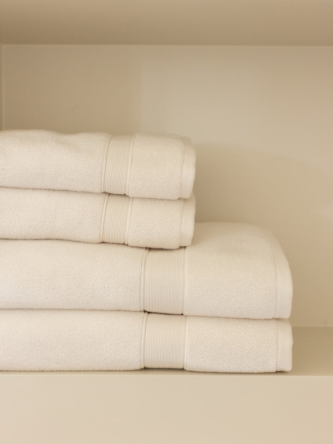 Seashell luxe bath towels and hand towels folded on shelf 