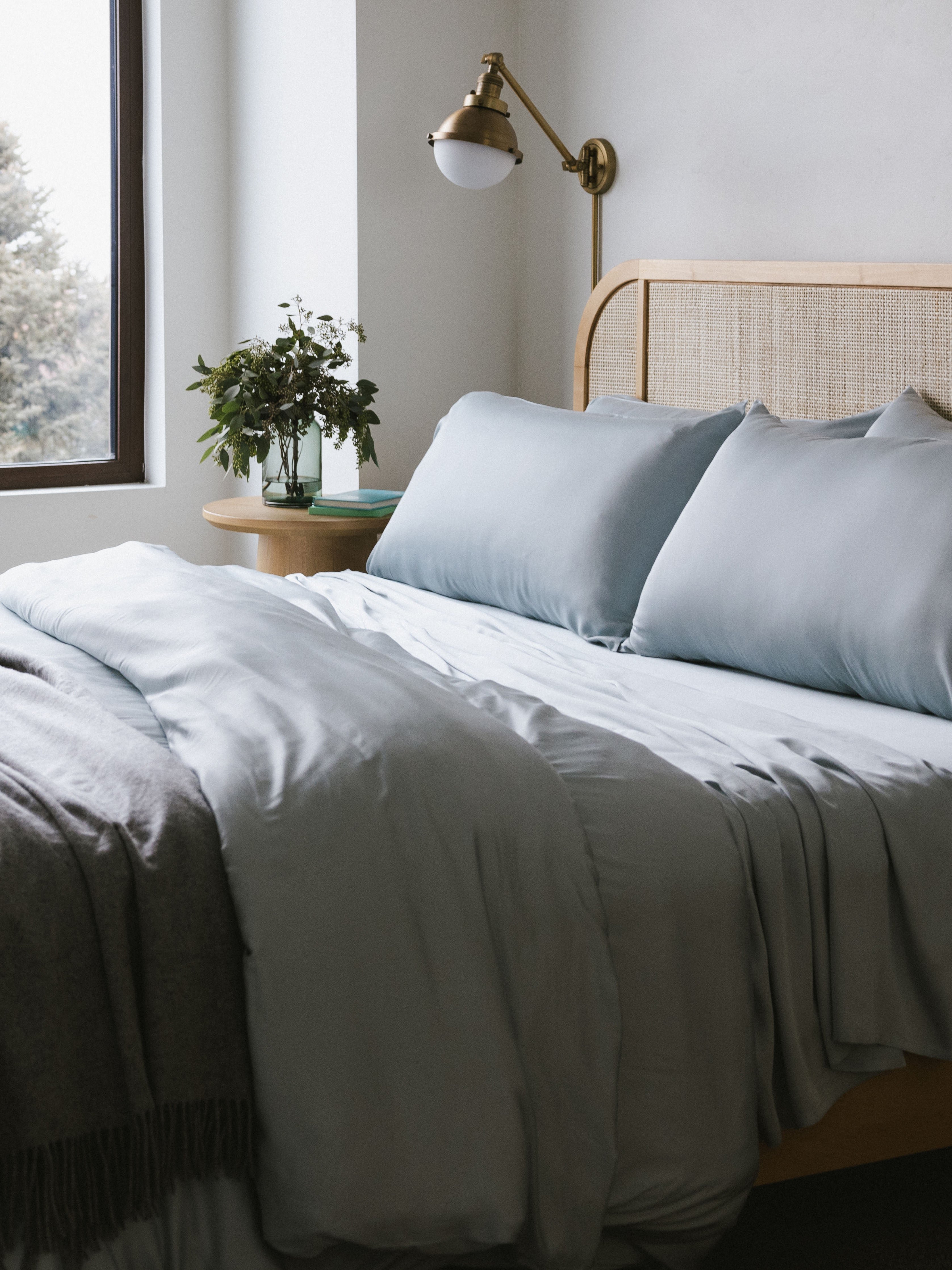 Shore bedding on a partially made bed with a throw blanket draped across 