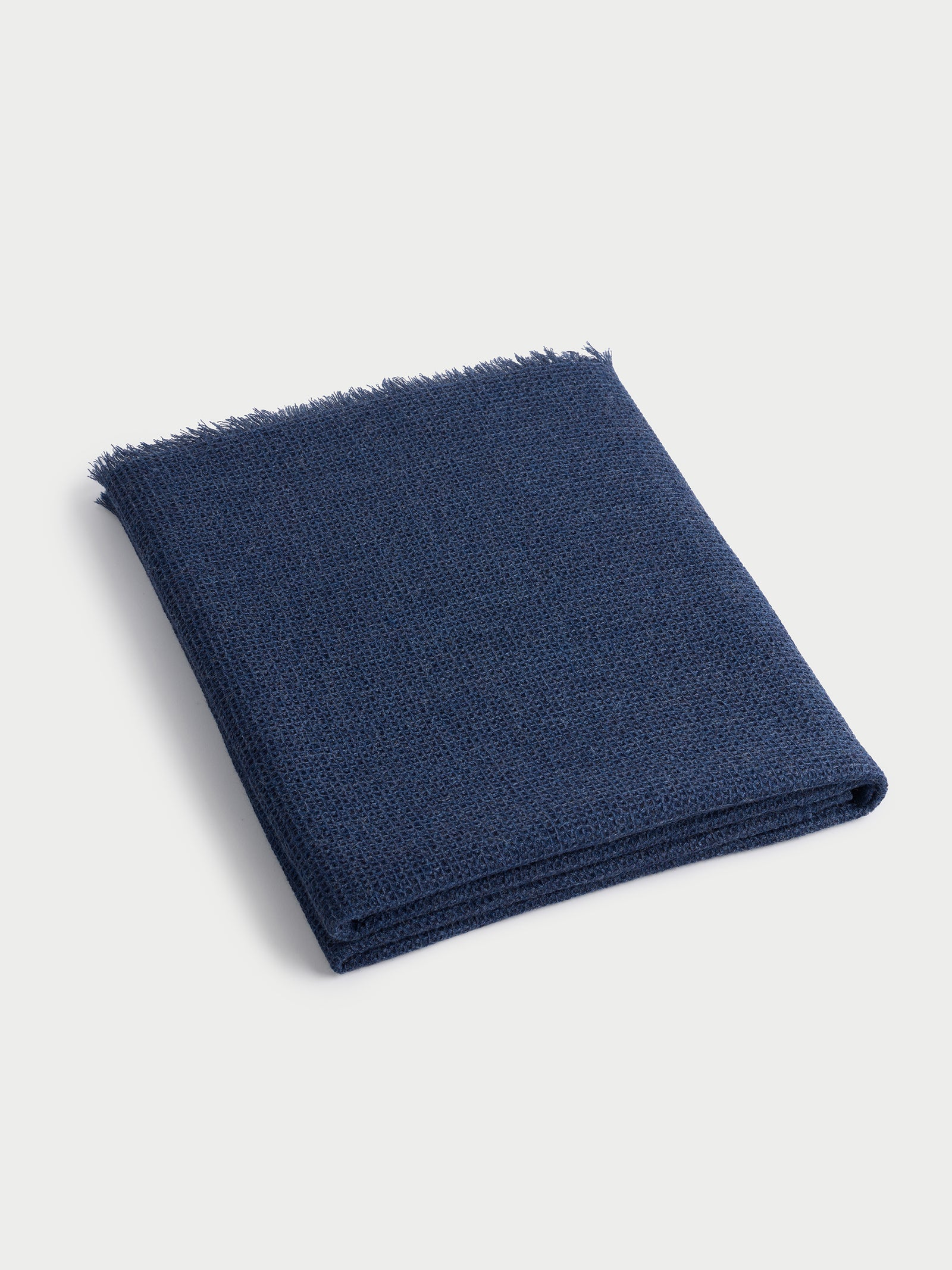 Folded alpaca throw in slate blue with white background 