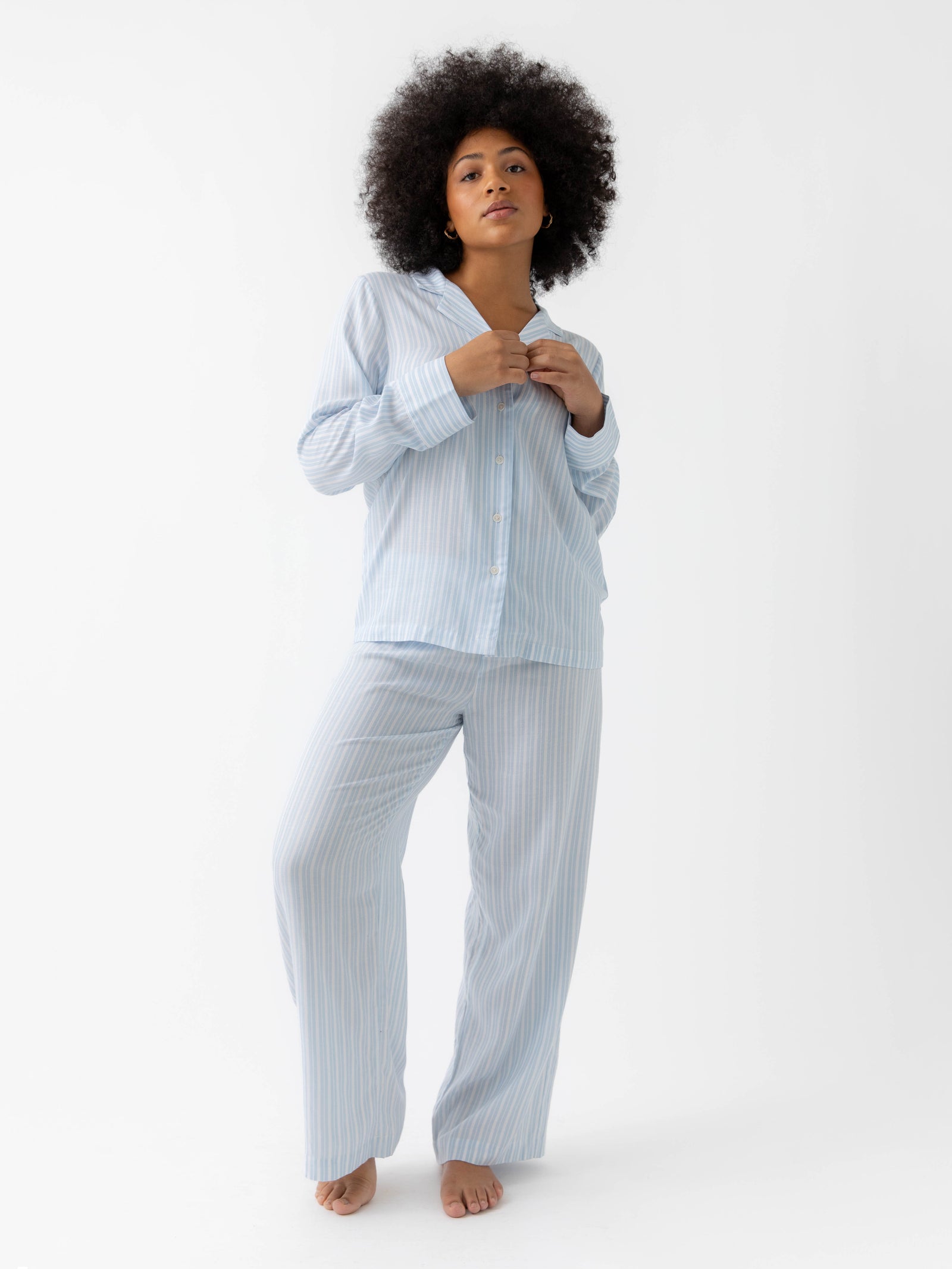 Woman wearing spring blue stripe pajama set with white background 