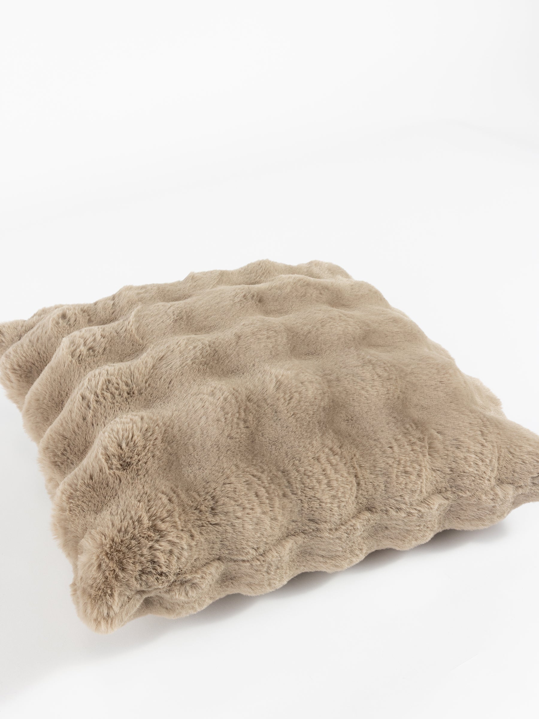 A Bubble Cuddle Pillow from Cozy Earth, featuring a fluffy beige design with a wavy texture, is placed on a white surface. Its soft, plush appearance adds a touch of coziness. |Color:Walnut