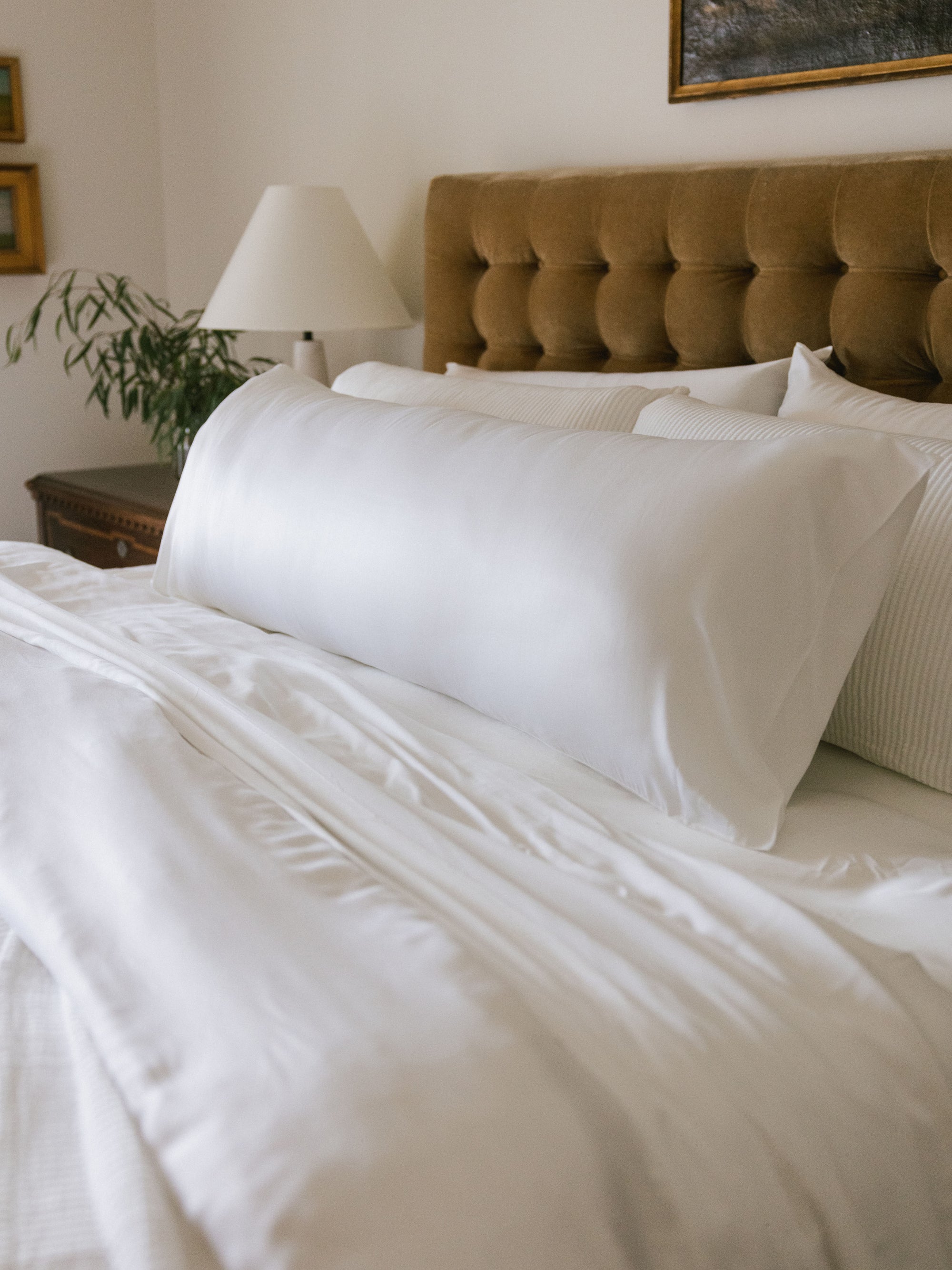 Side view of body pillow with white case on bed 